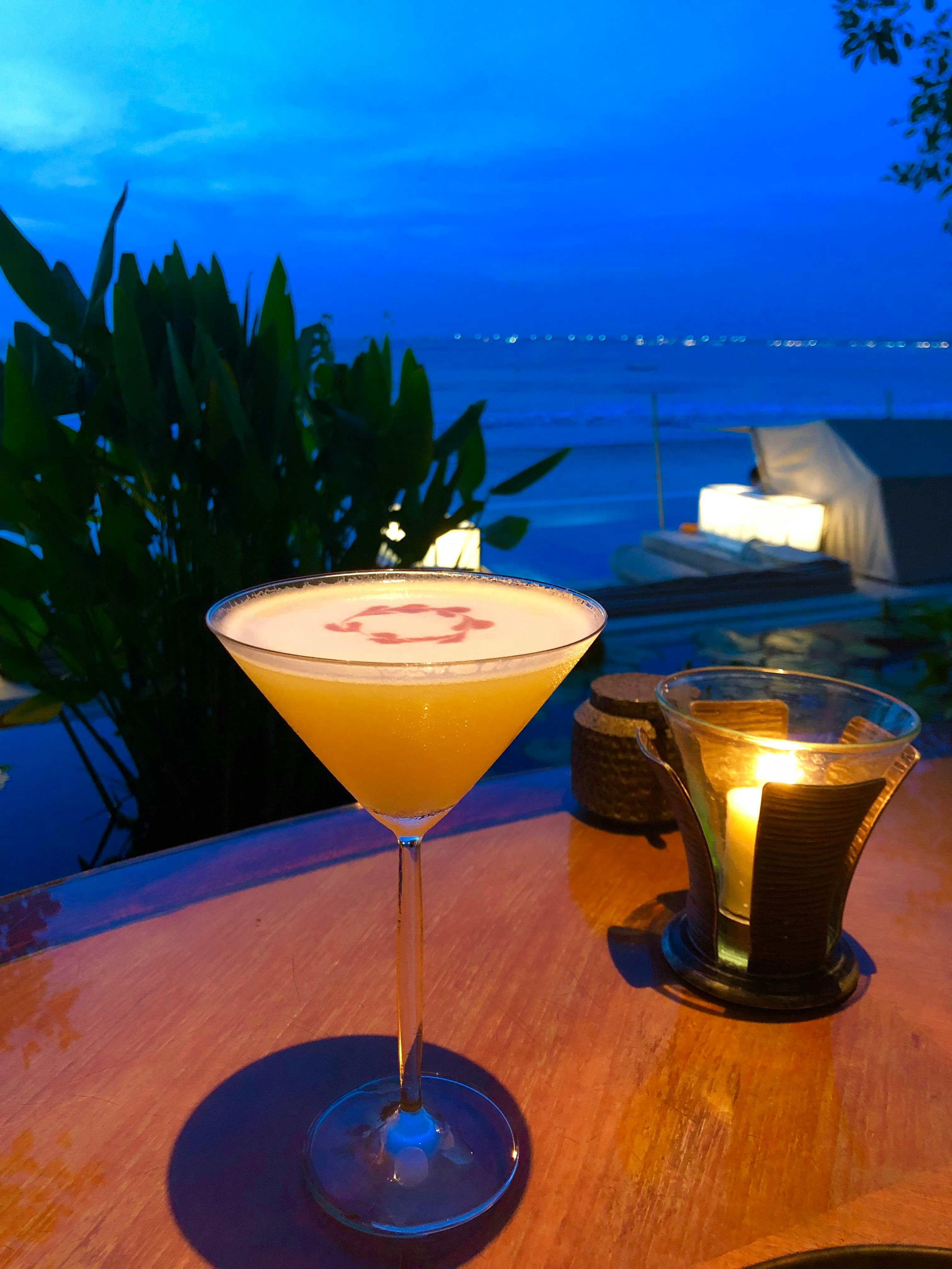 orange liquid in clear martini glass on brown wooden surface