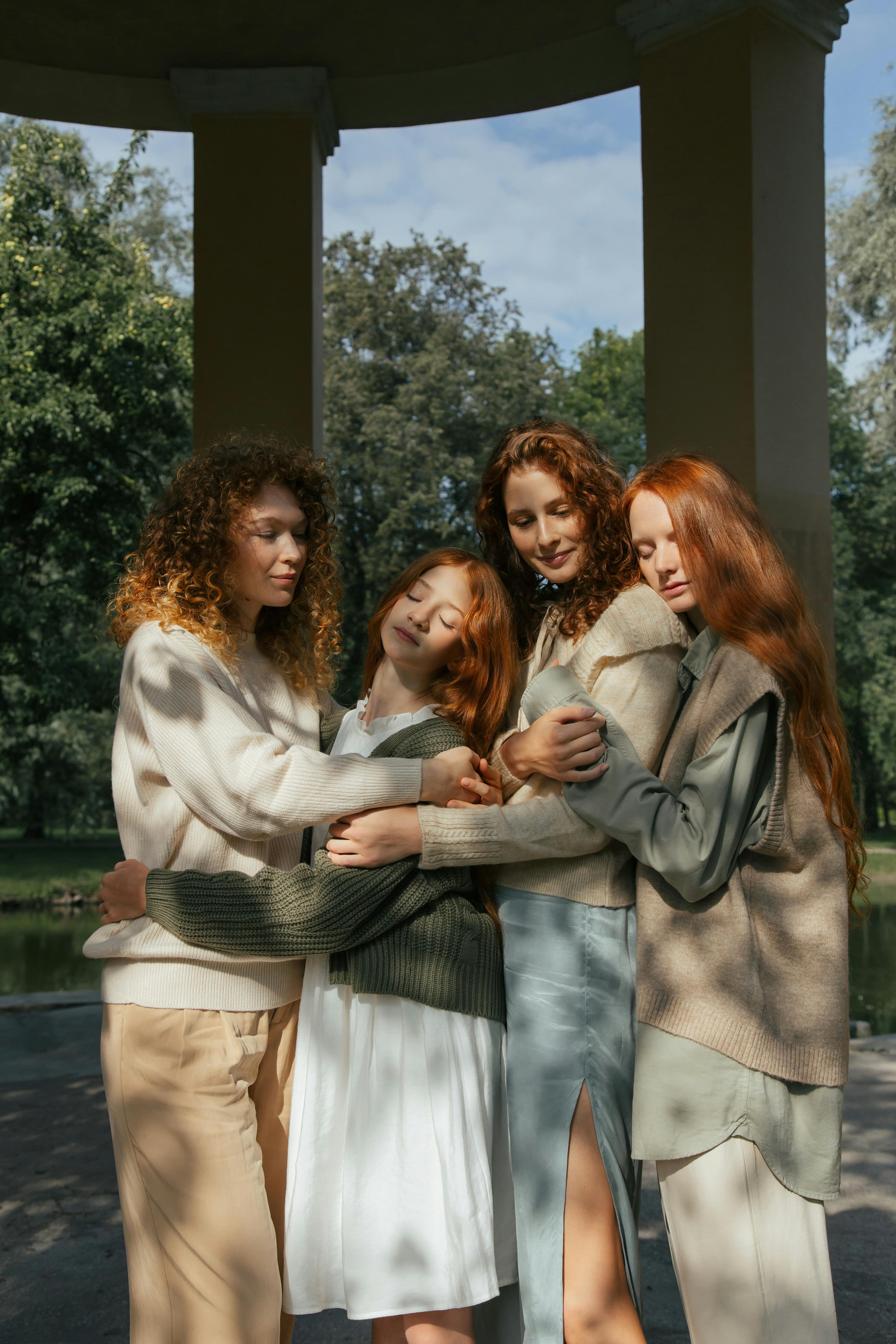 four female friends hugging in park