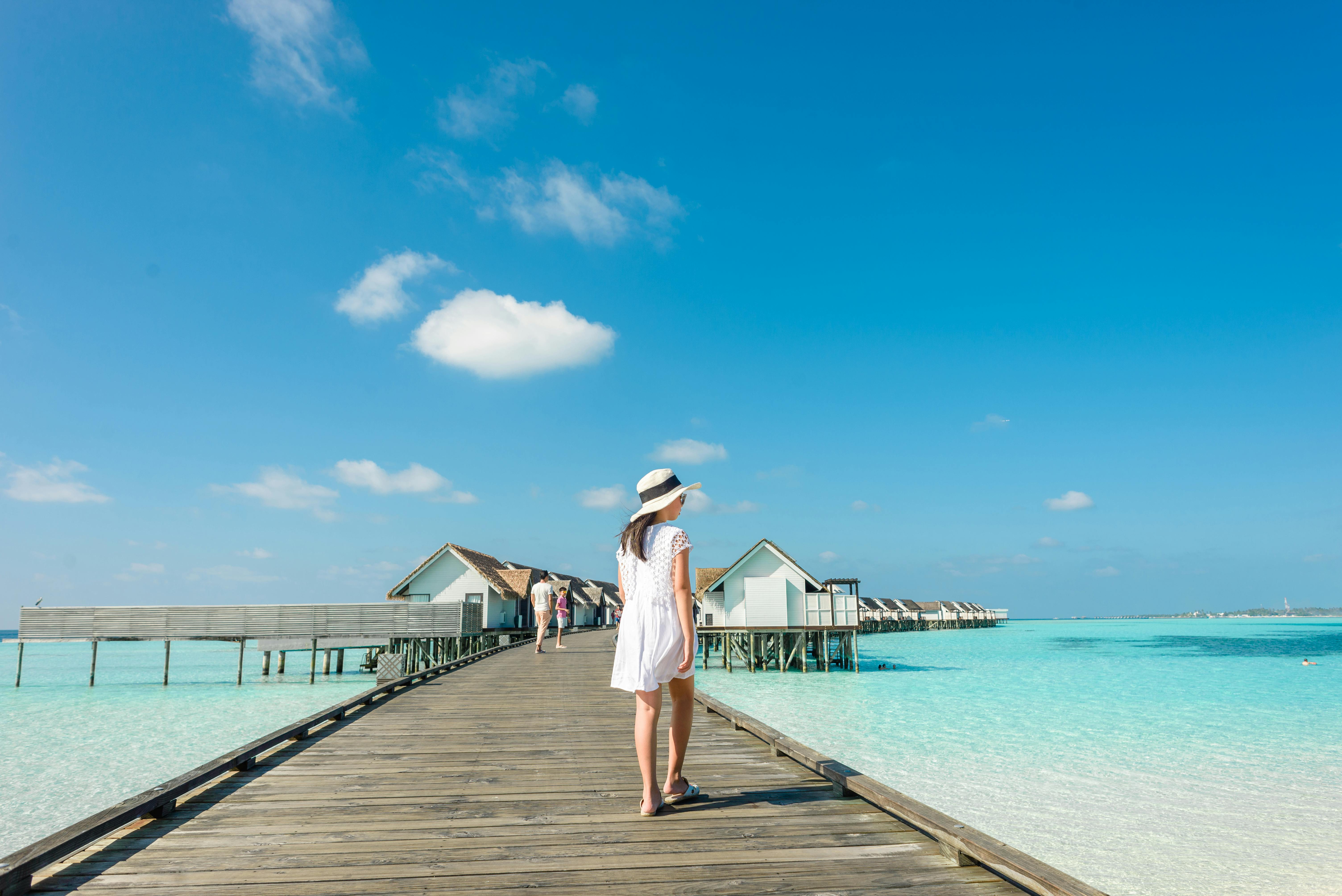 back view of a woman in white dress walking on wooden dock