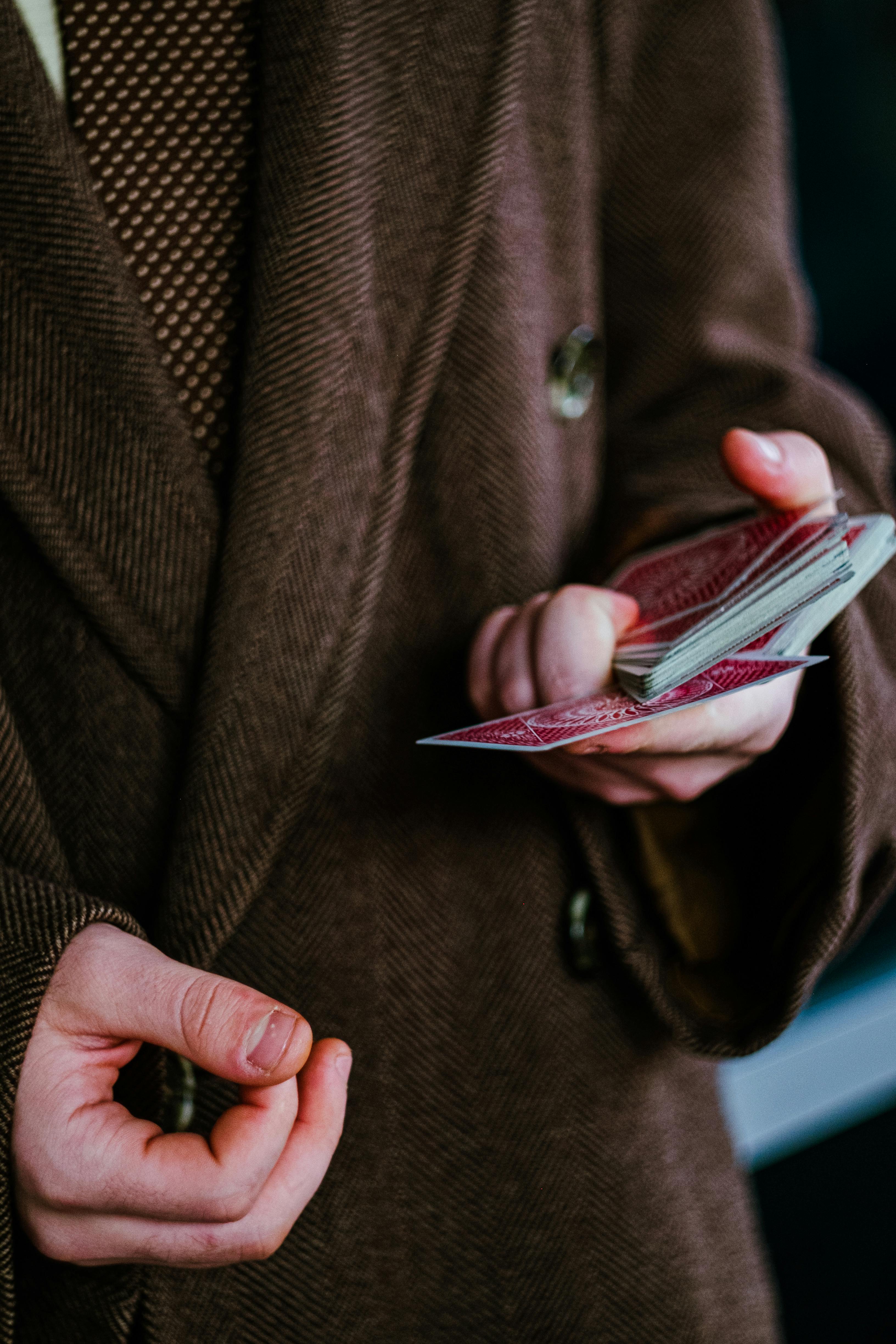 a person in brown suit holding playing cards