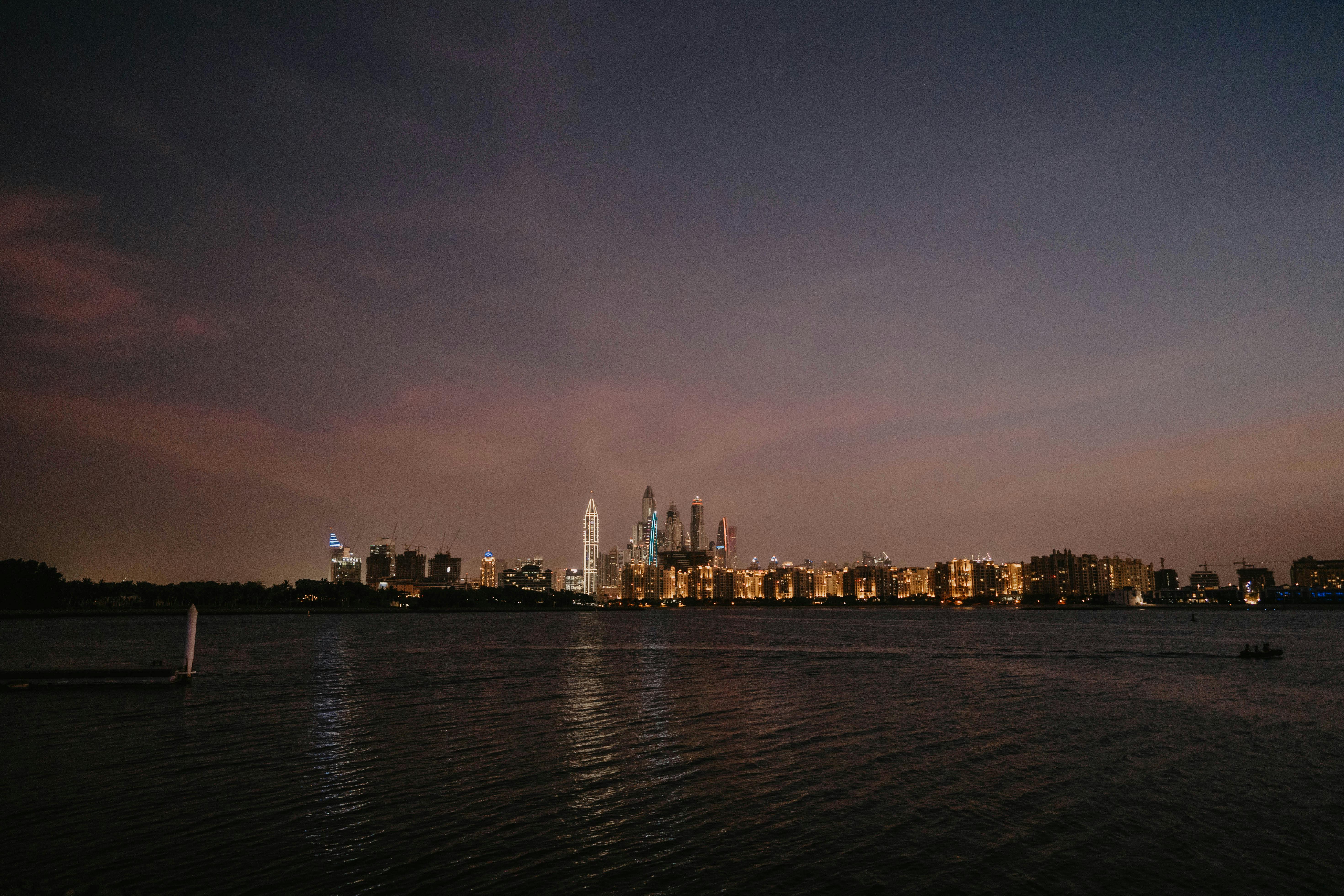 a city skyline at night with a body of water in the background