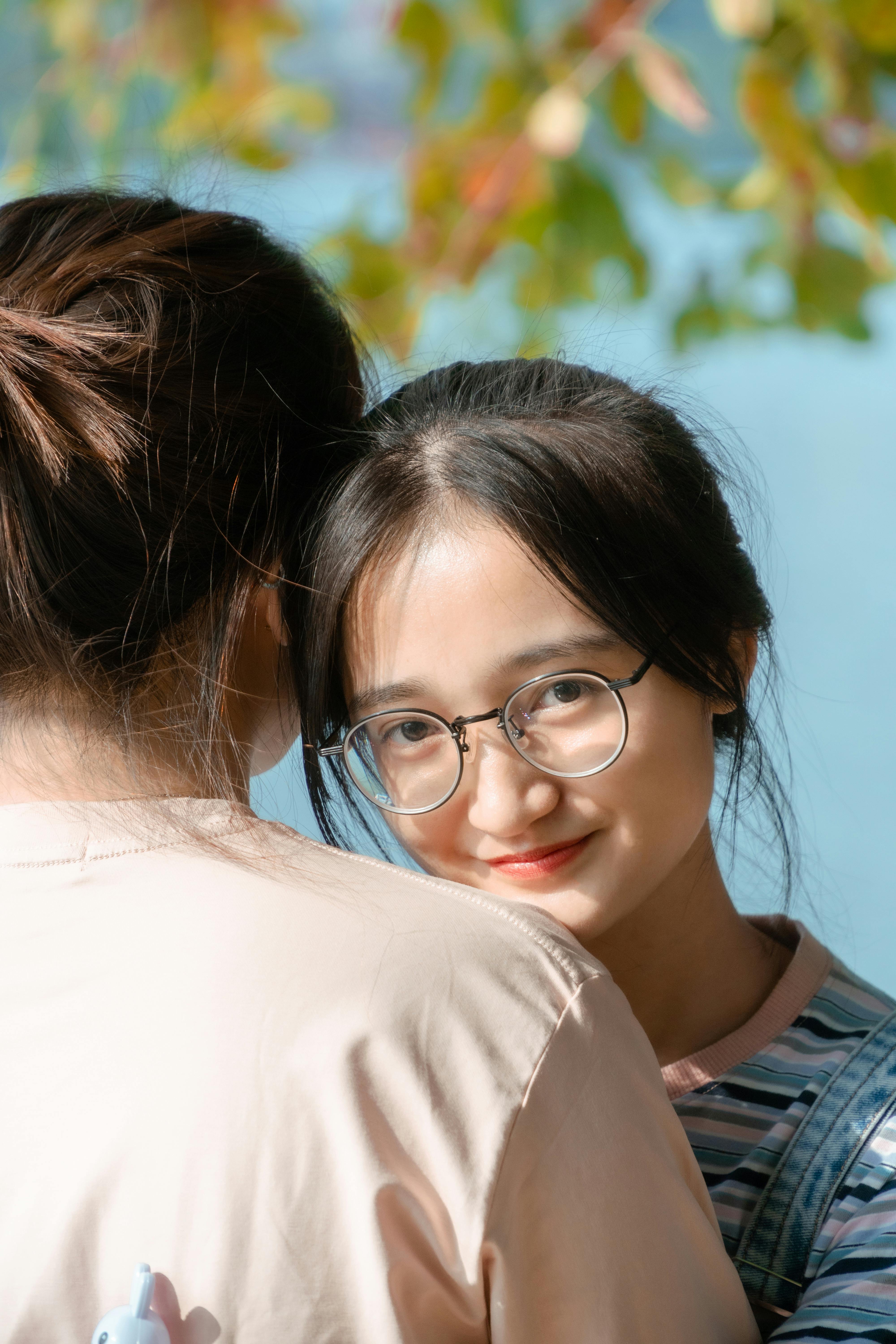 girl in glasses hugging friend outdoors