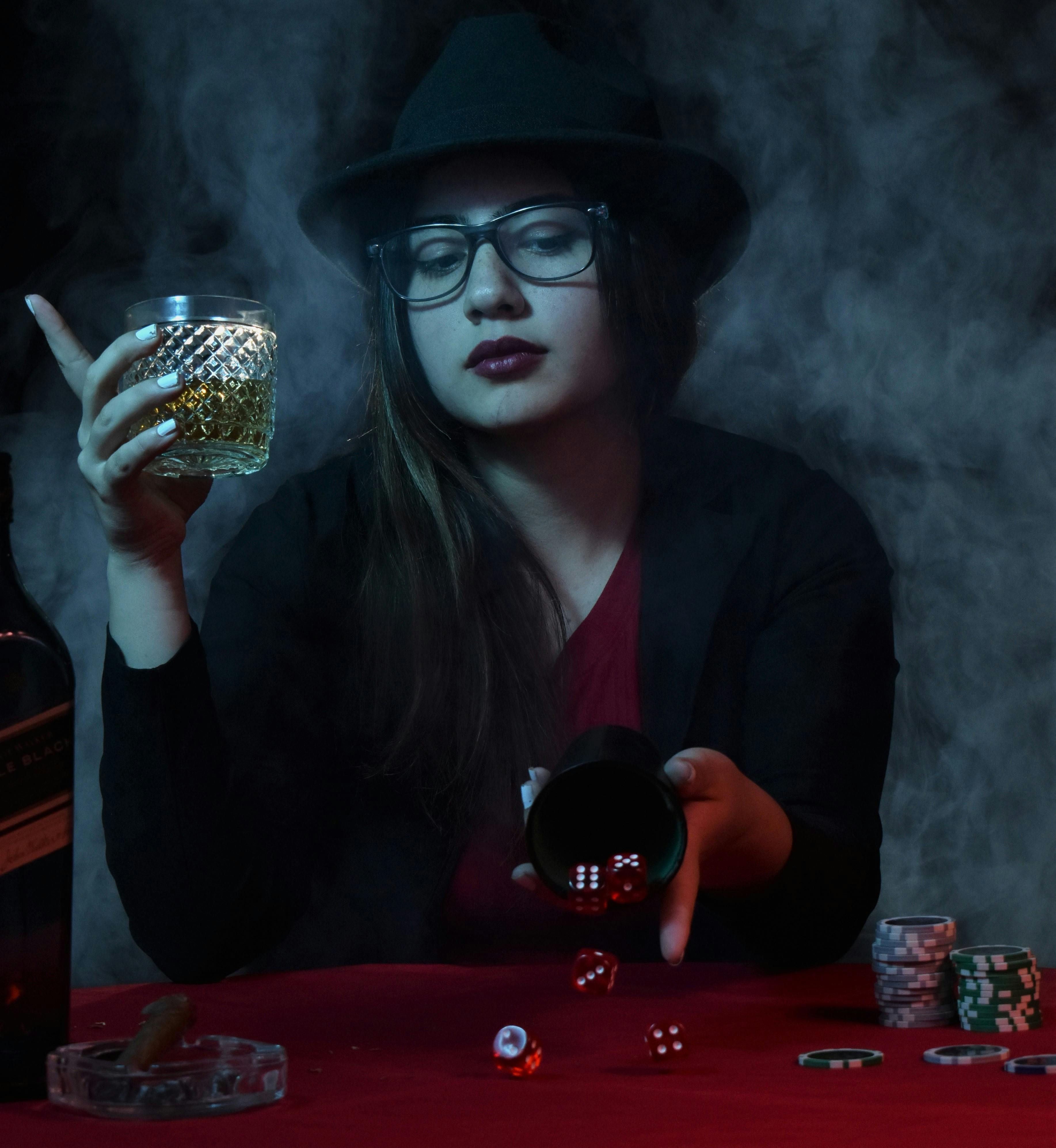 woman throwing dice on a table and holding a drink