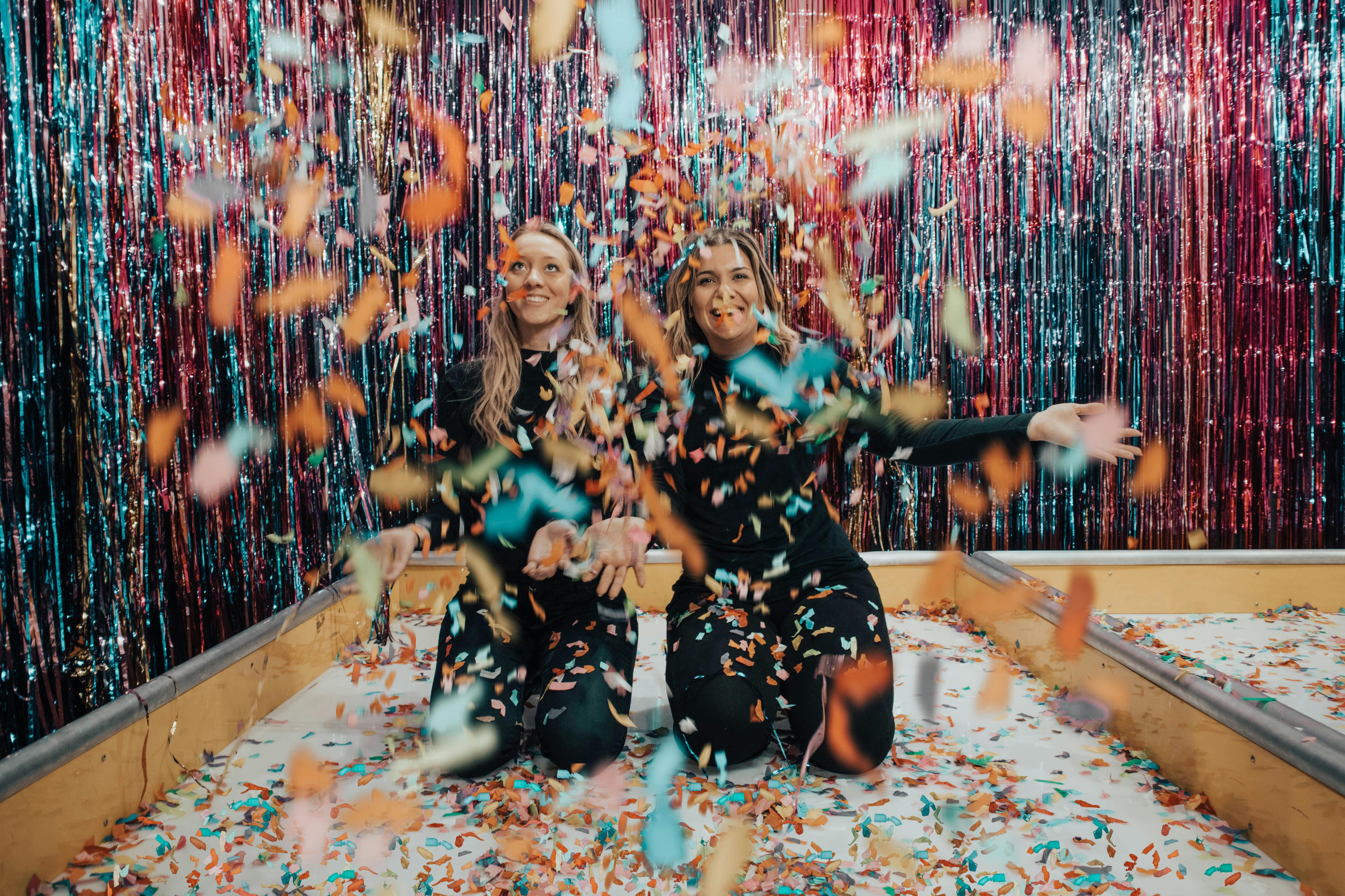 two women kneeling while throwing confetti