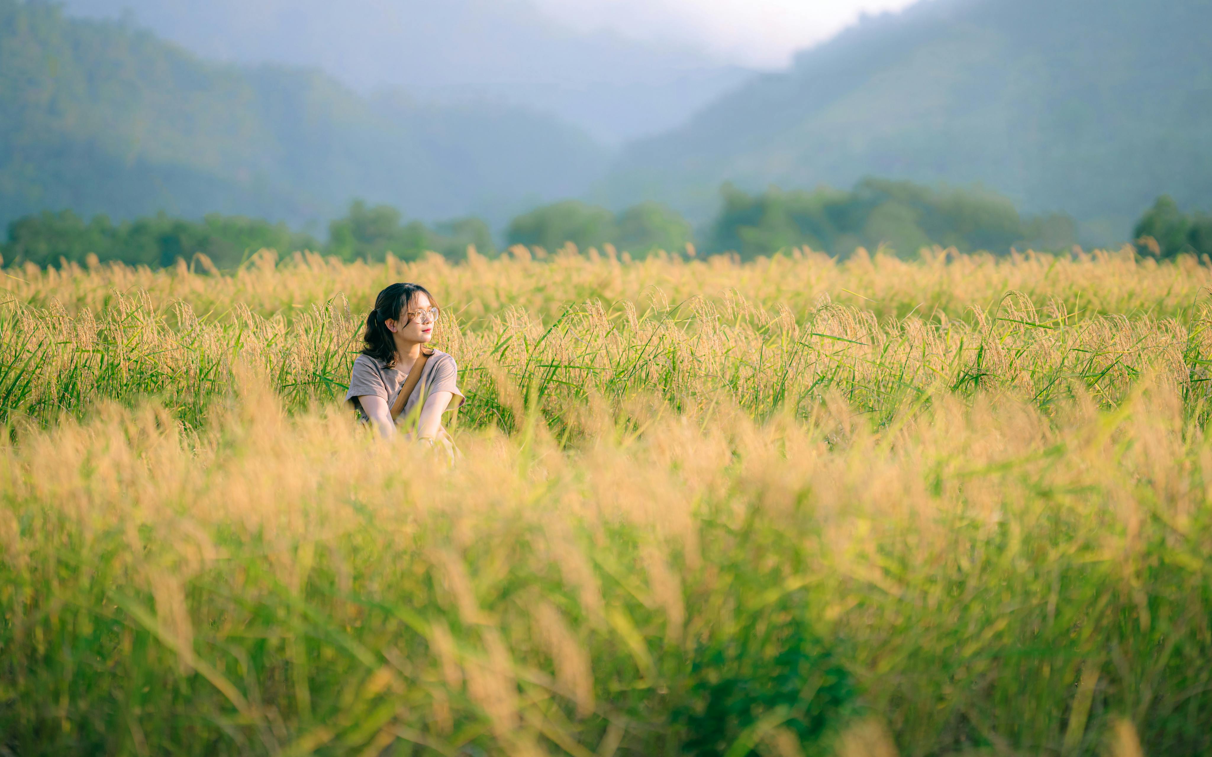 young woman sitting on a grass field in a valley