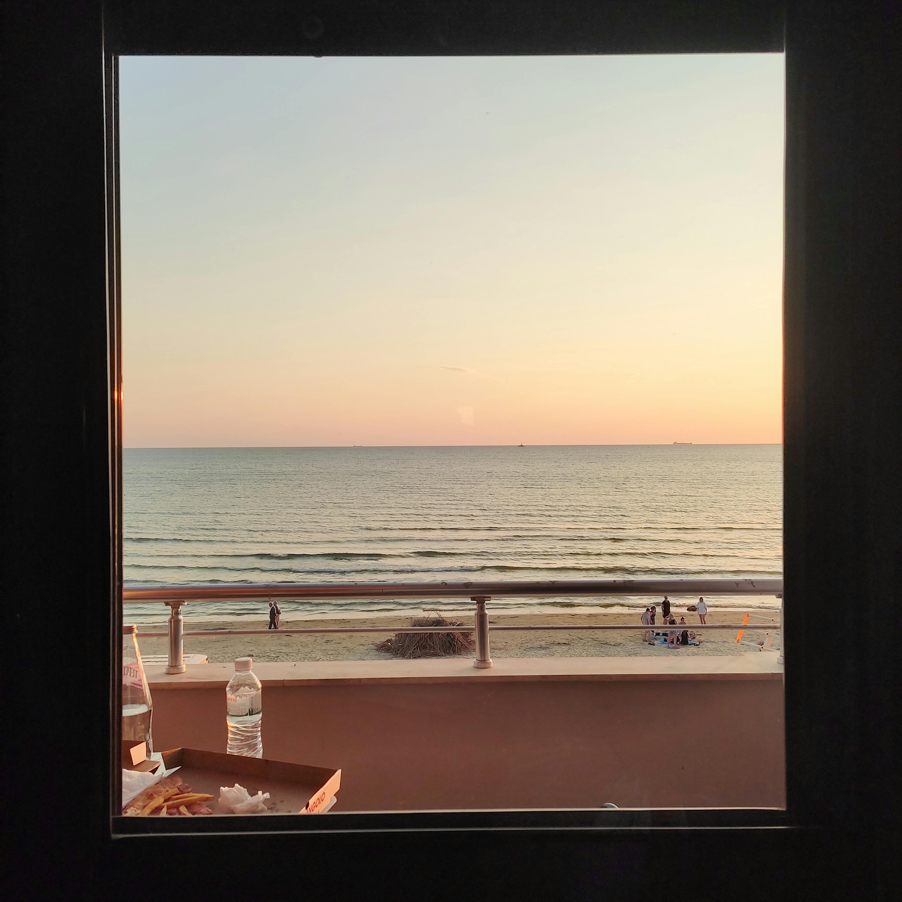 sea coast behind window at sunset