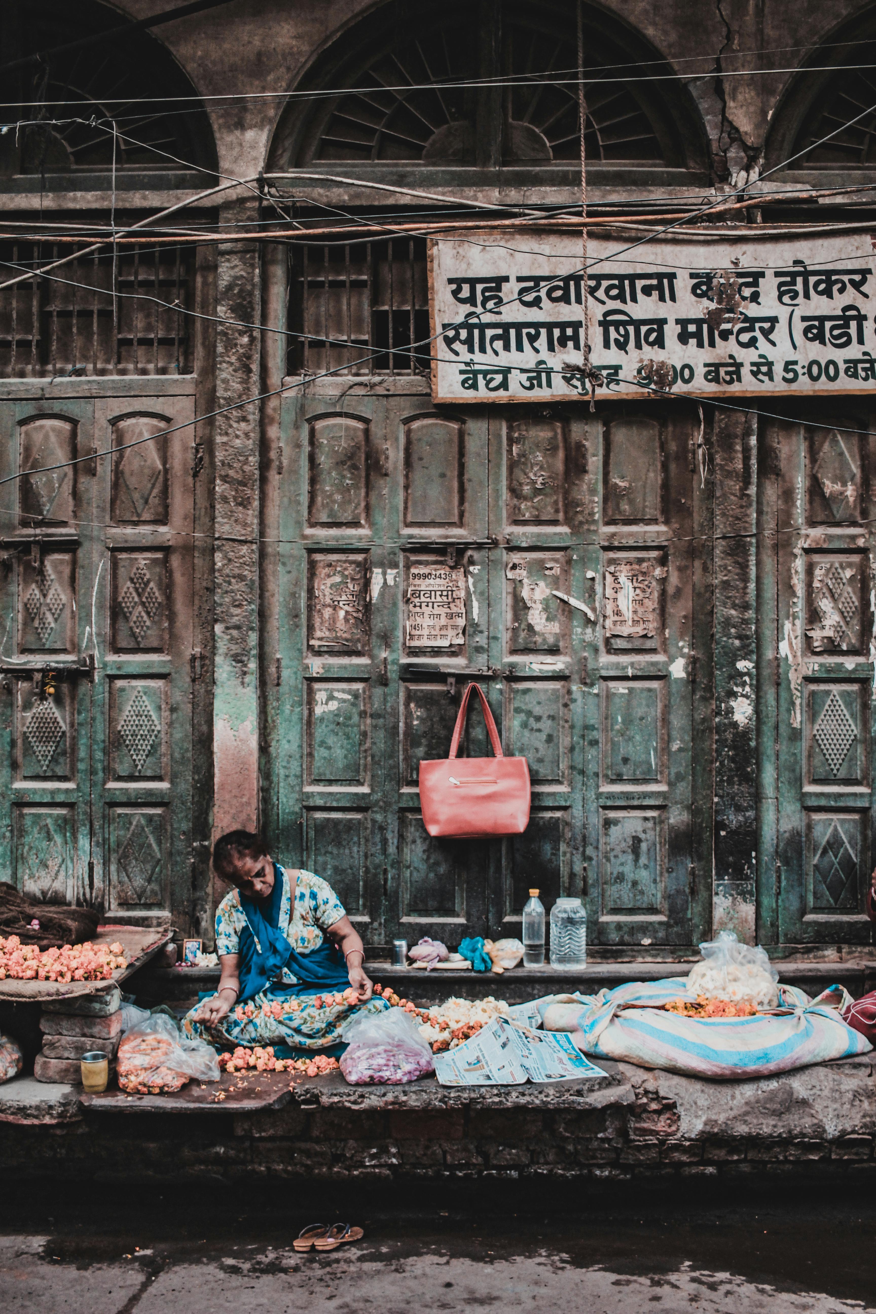 woman sitting on sidewalk selling fruits and vegetables