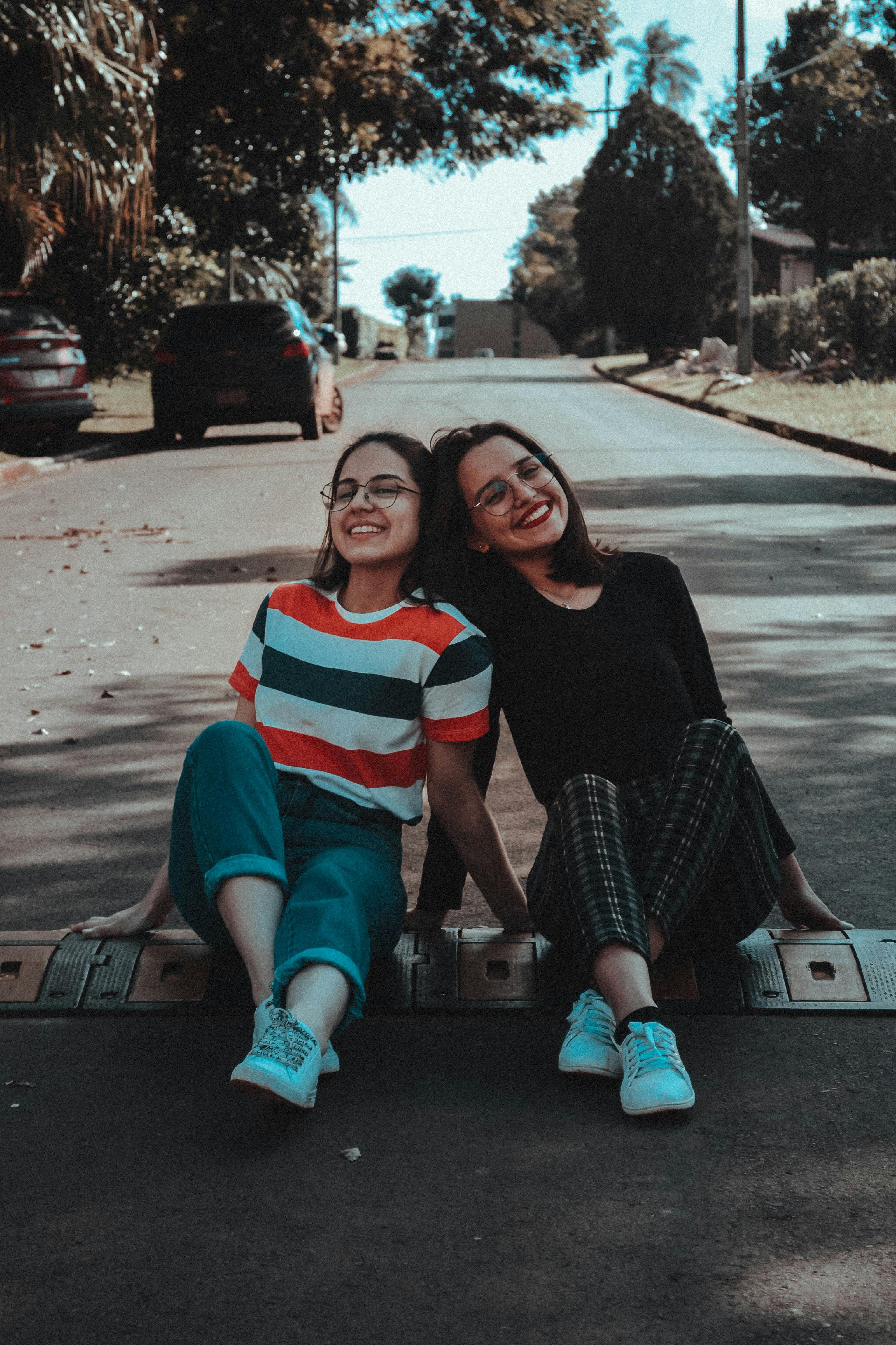 photo of two women sitting on road