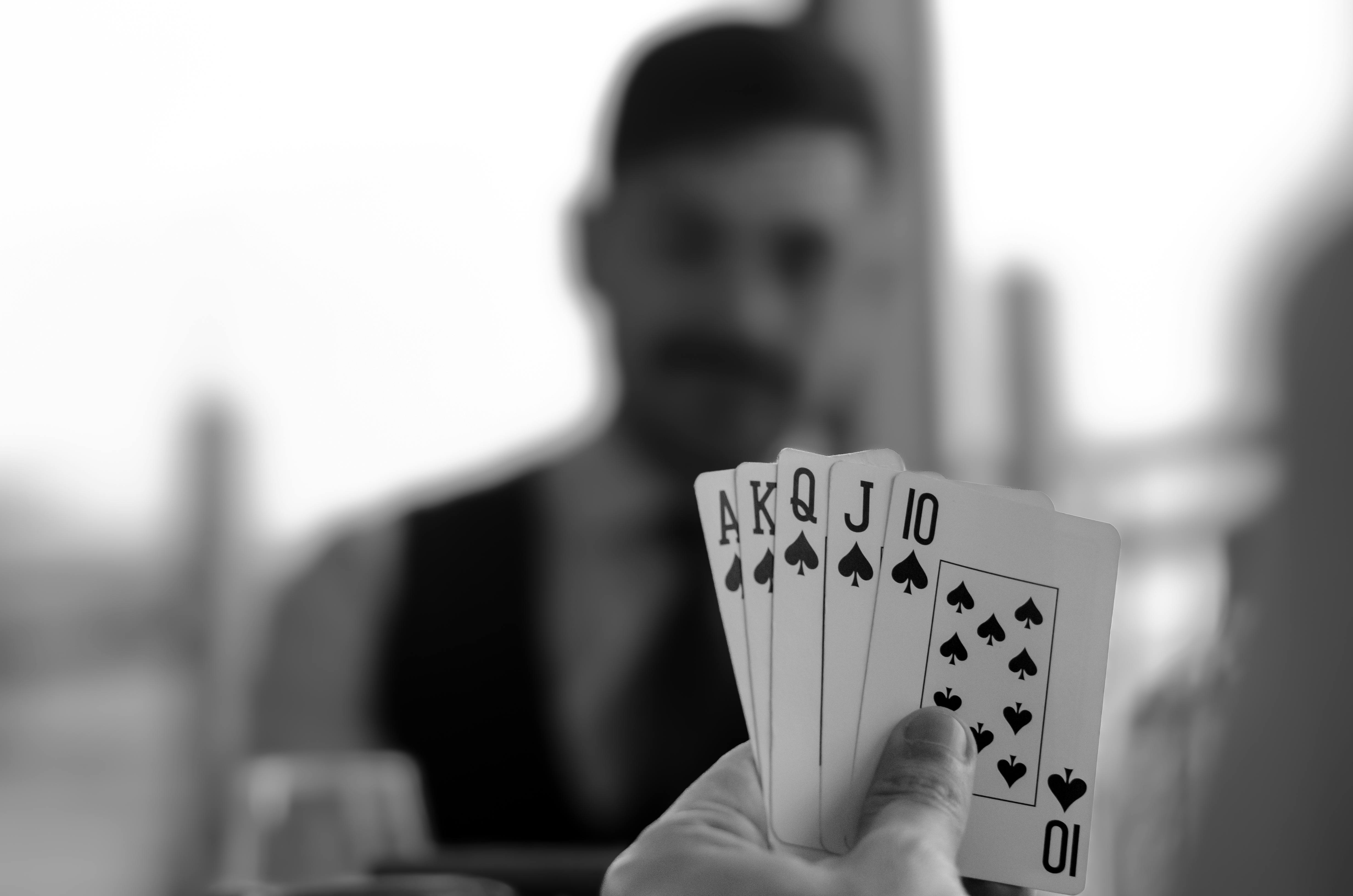 black and white photo of a man holding four playing cards