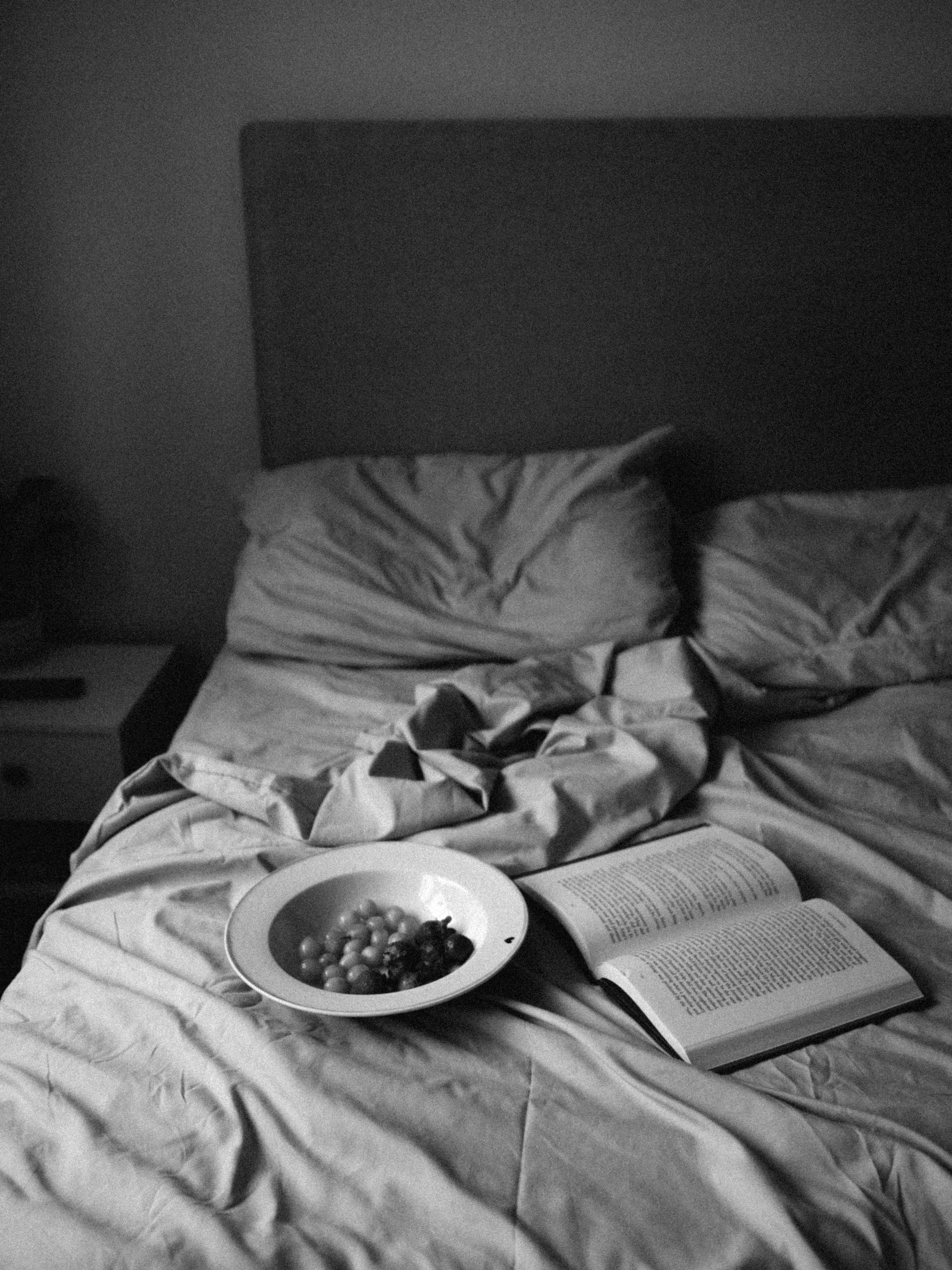 grapes on a plate and an open book on a bed