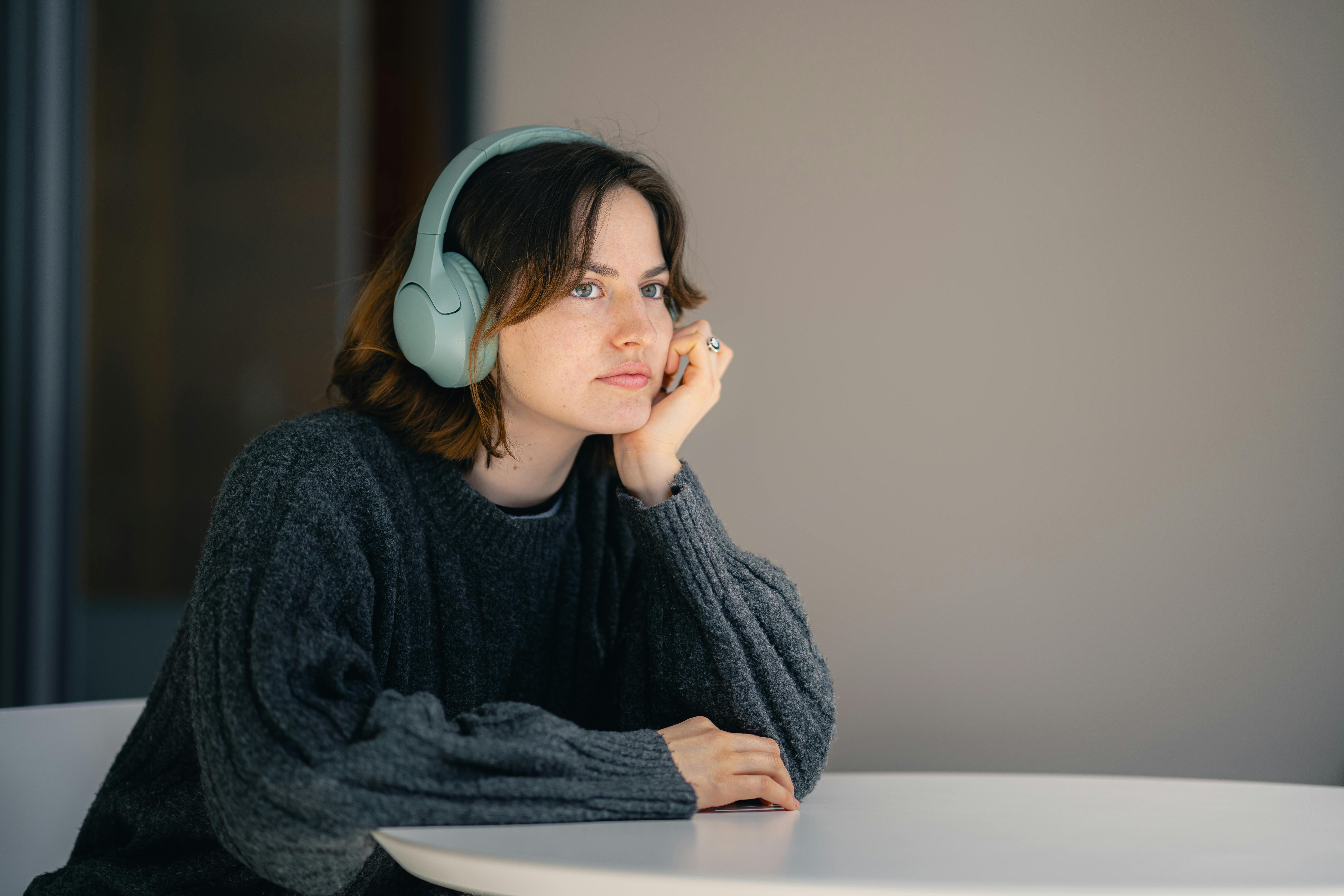 thoughtful woman with headphones at table