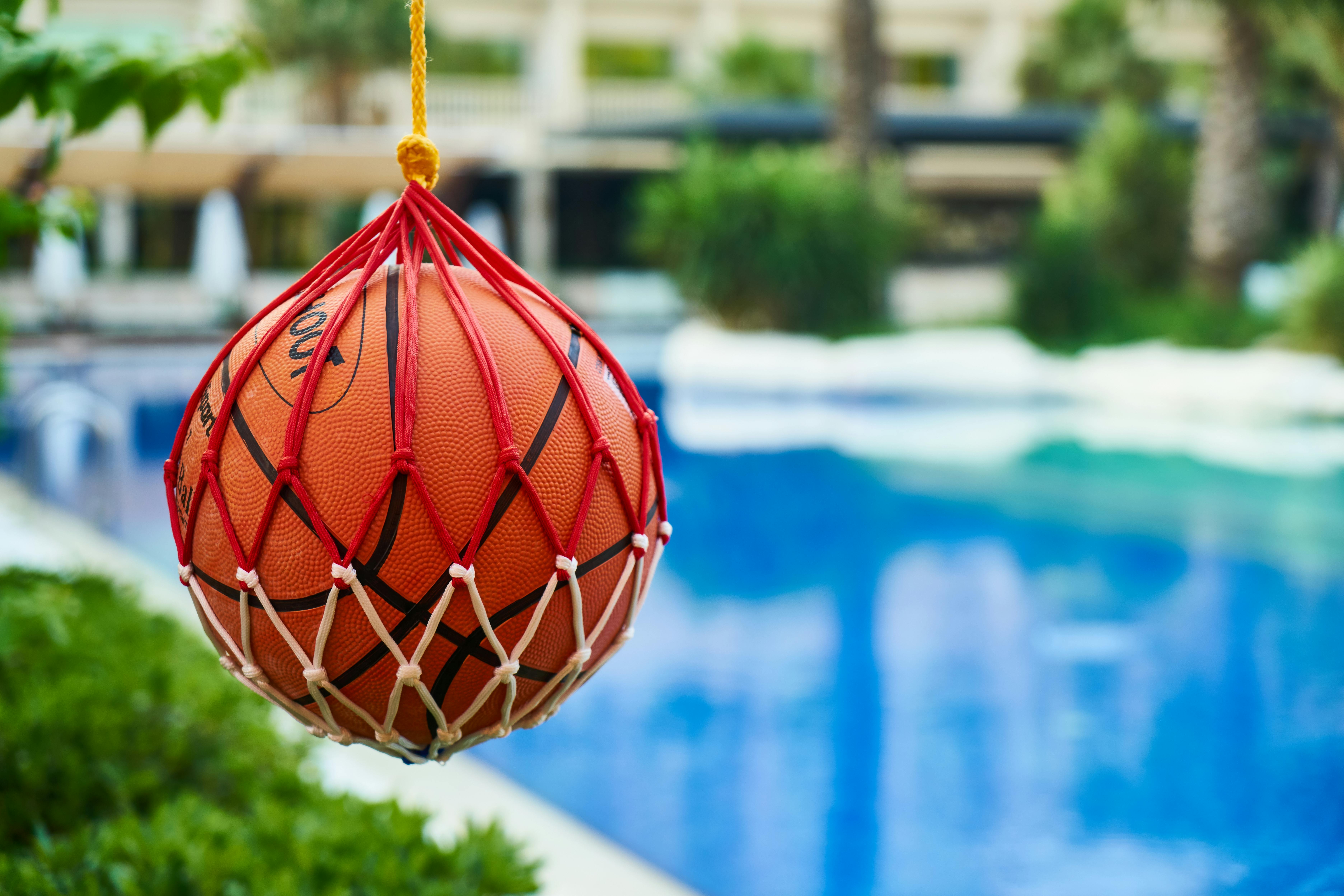 shallow focus photography of orange basketball hanging in a net