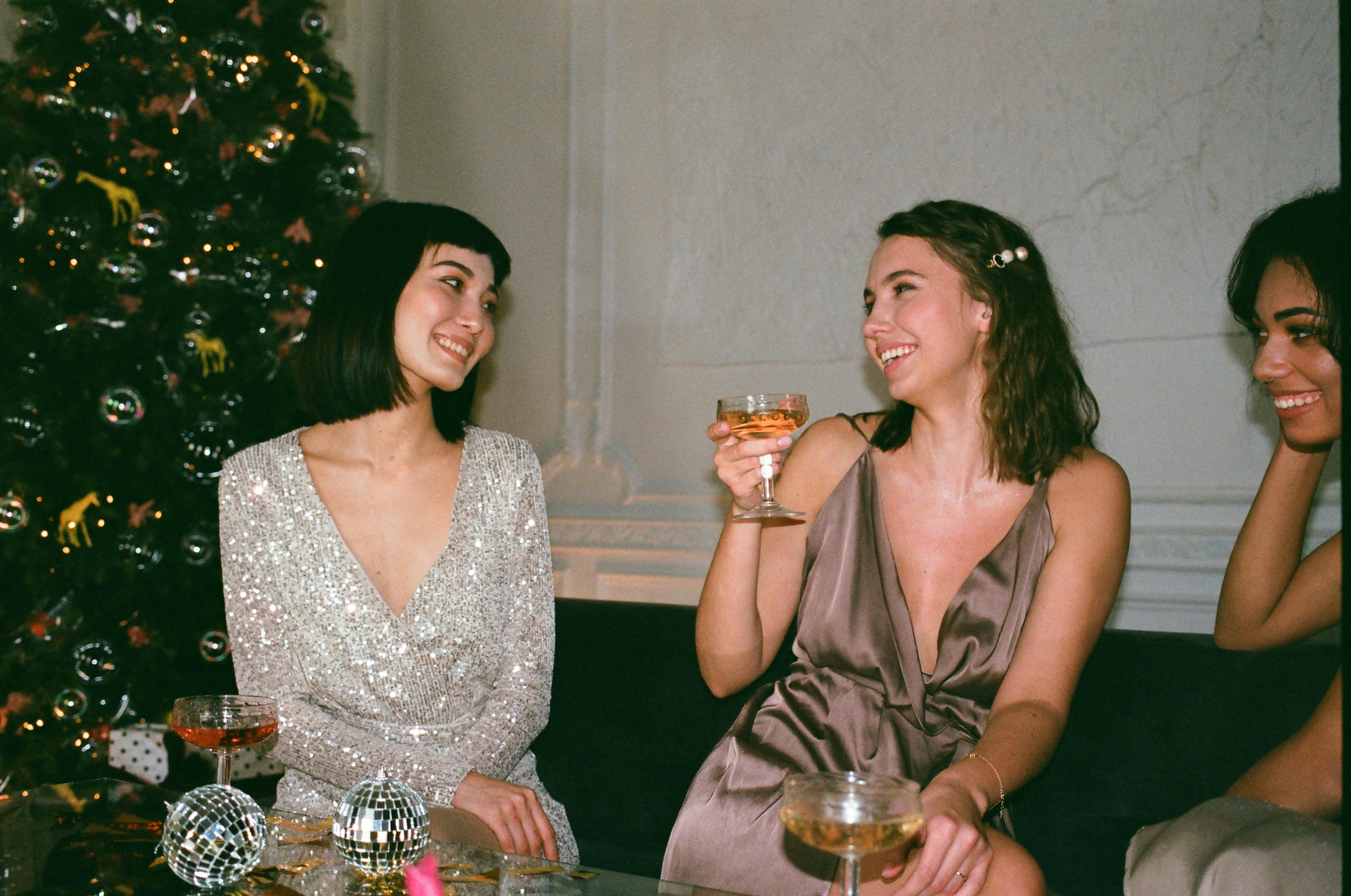 three women laughing beside christmas tree