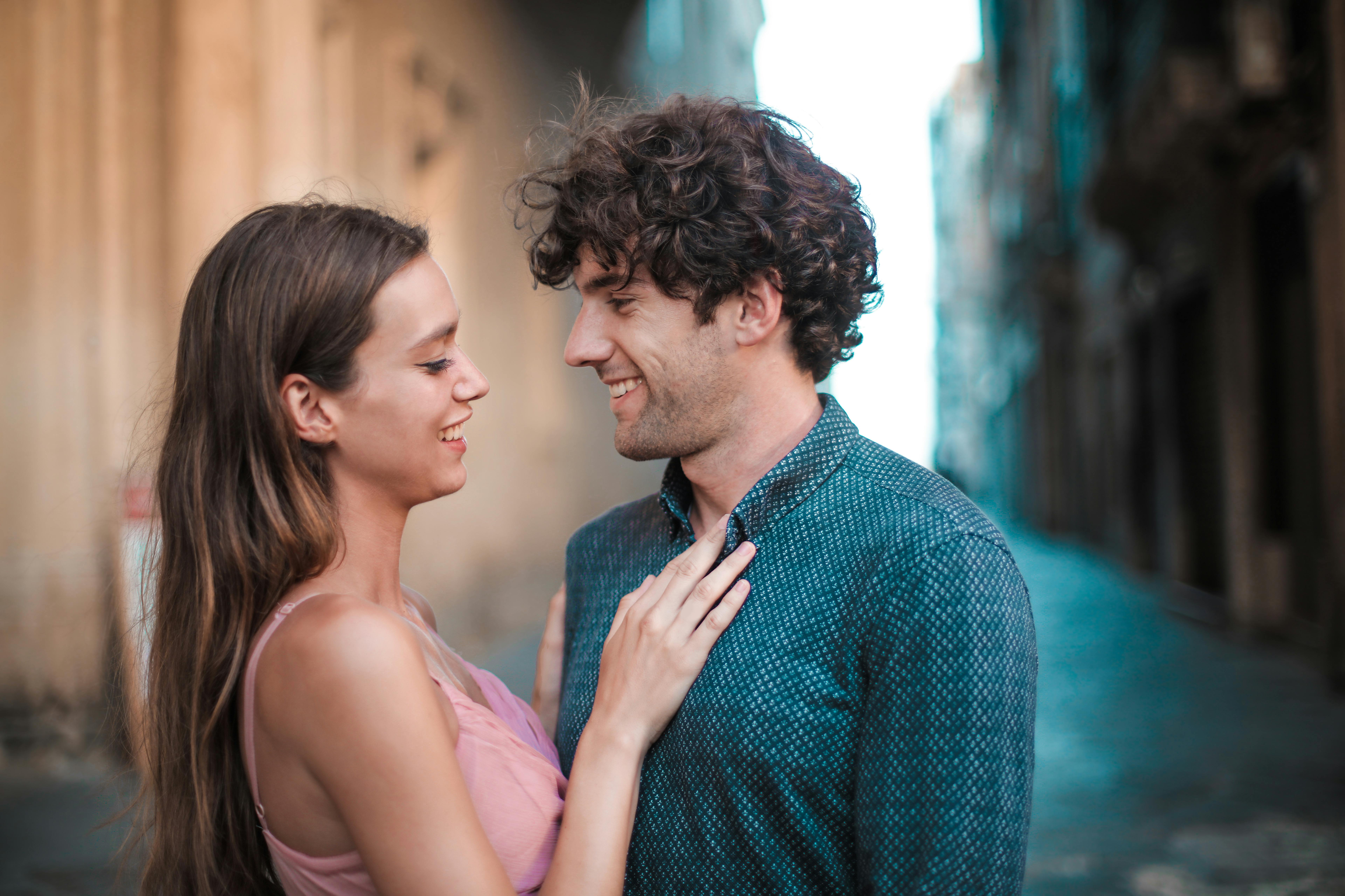 man wearing blue shirt kissing woman in pink tank top