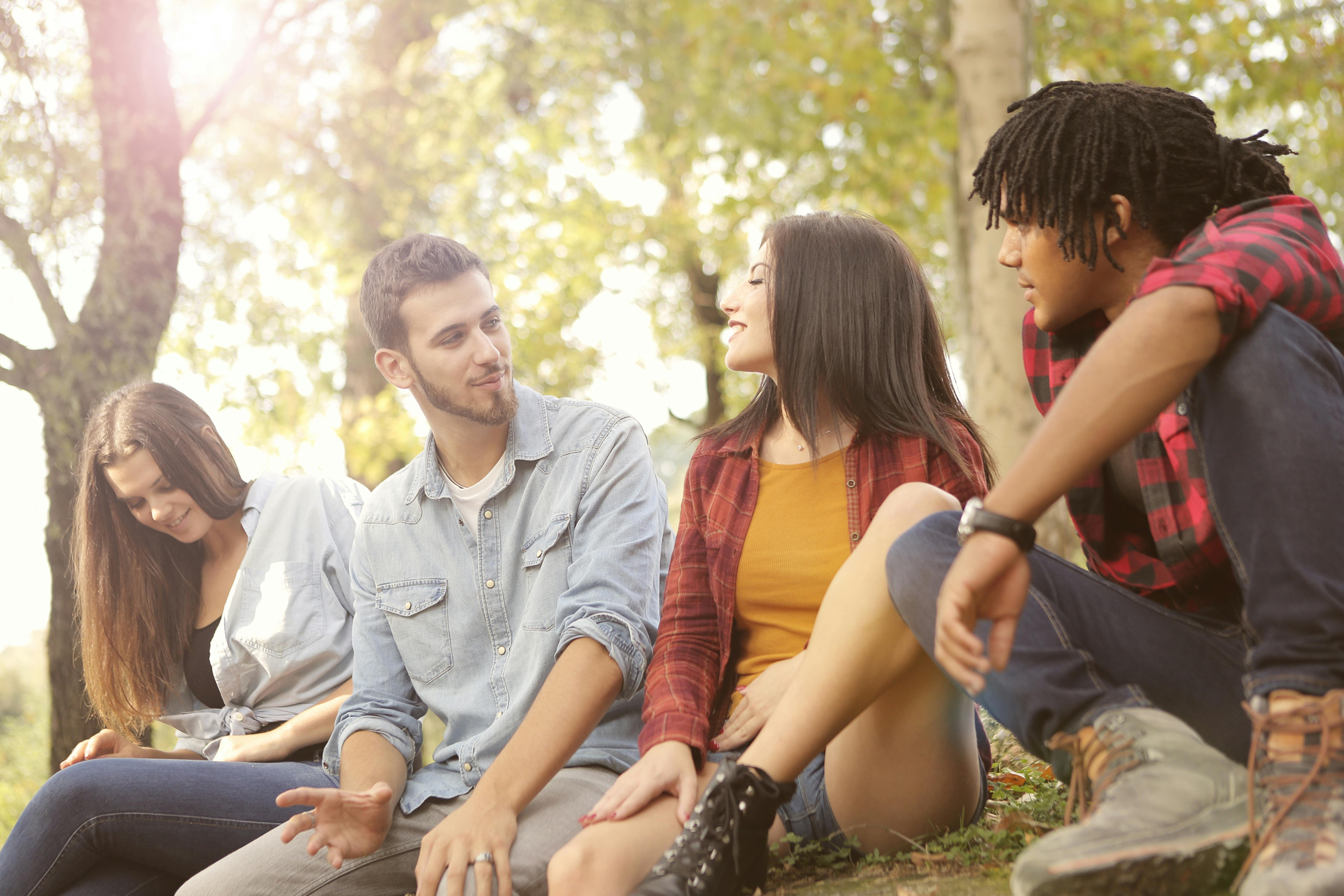 happy multiethnic friends sitting in park