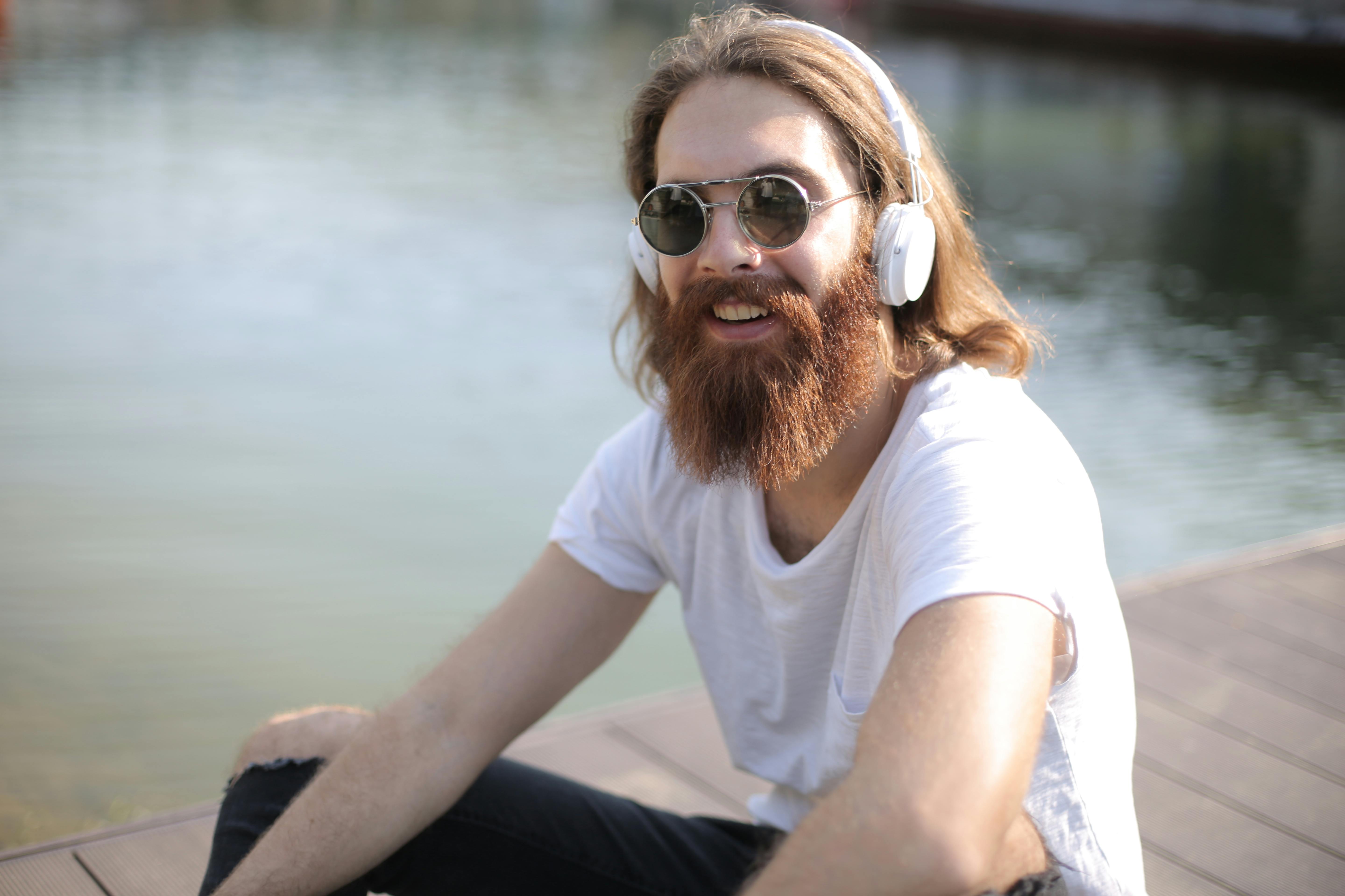 man in white crew neck t shirt listening music on white headphones