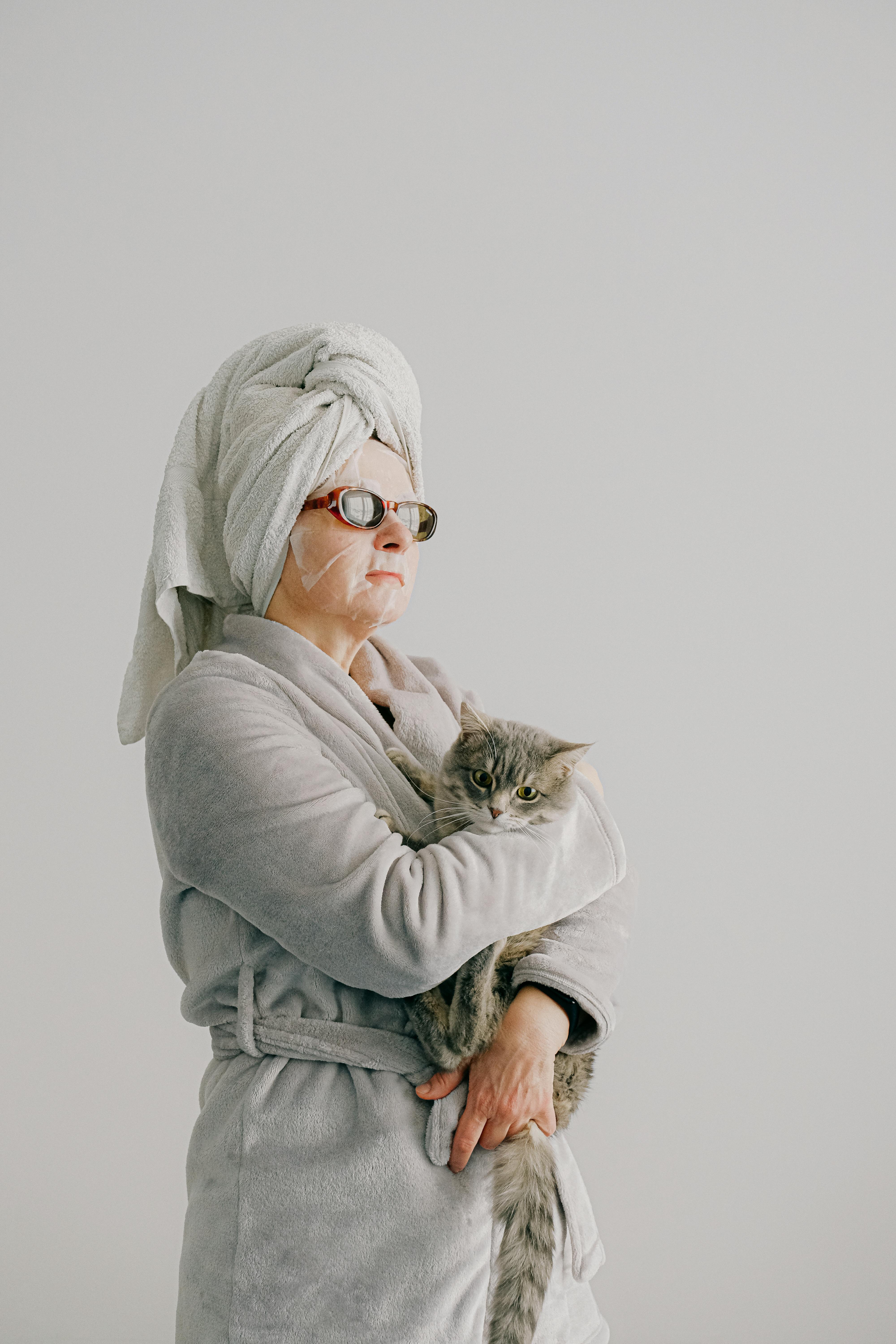 woman after bath standing with cat in arms