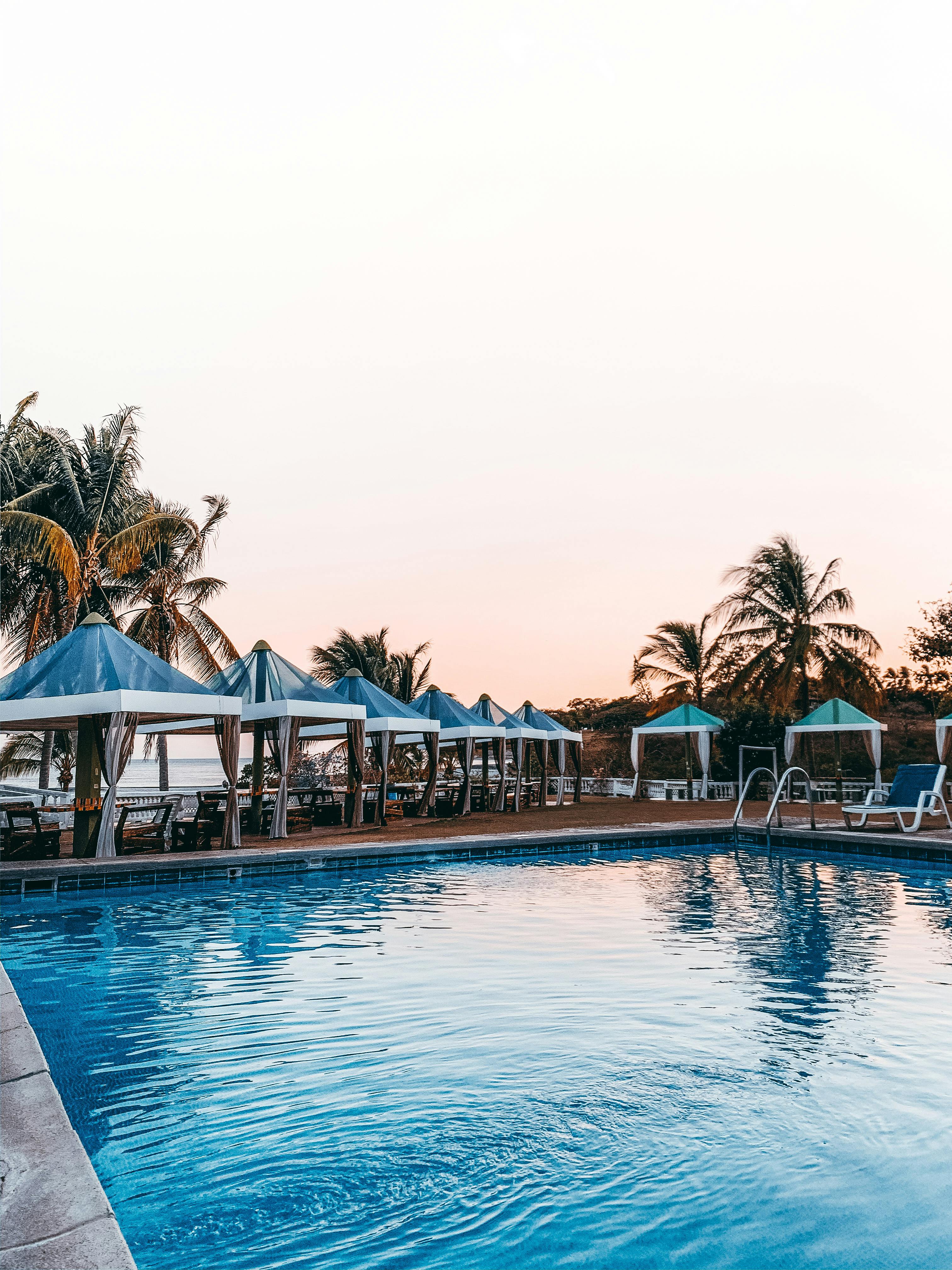 peaceful empty poolside with palms and umbrellas in tropical resort