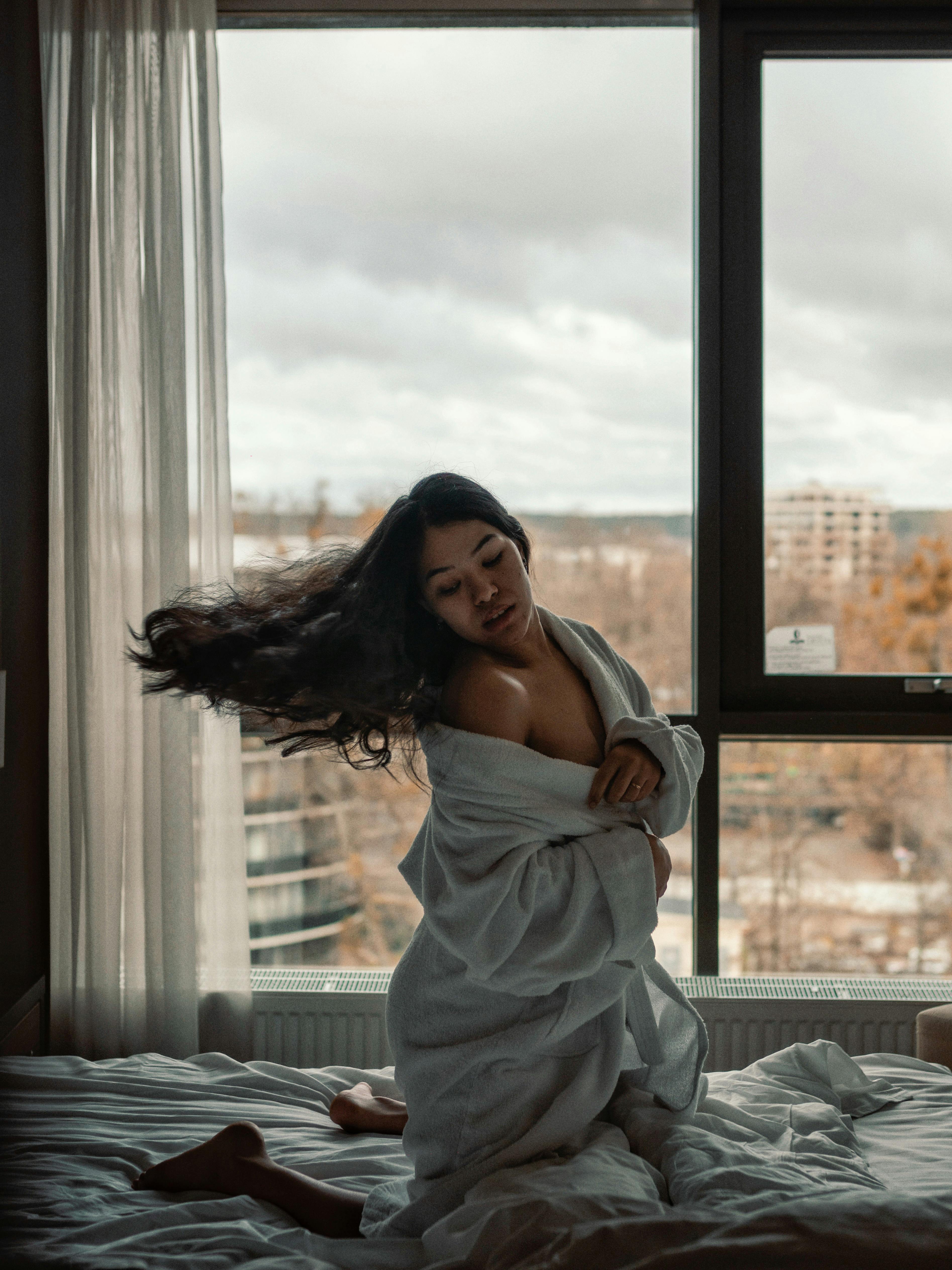 woman wearing bathrobe while flipping her hair