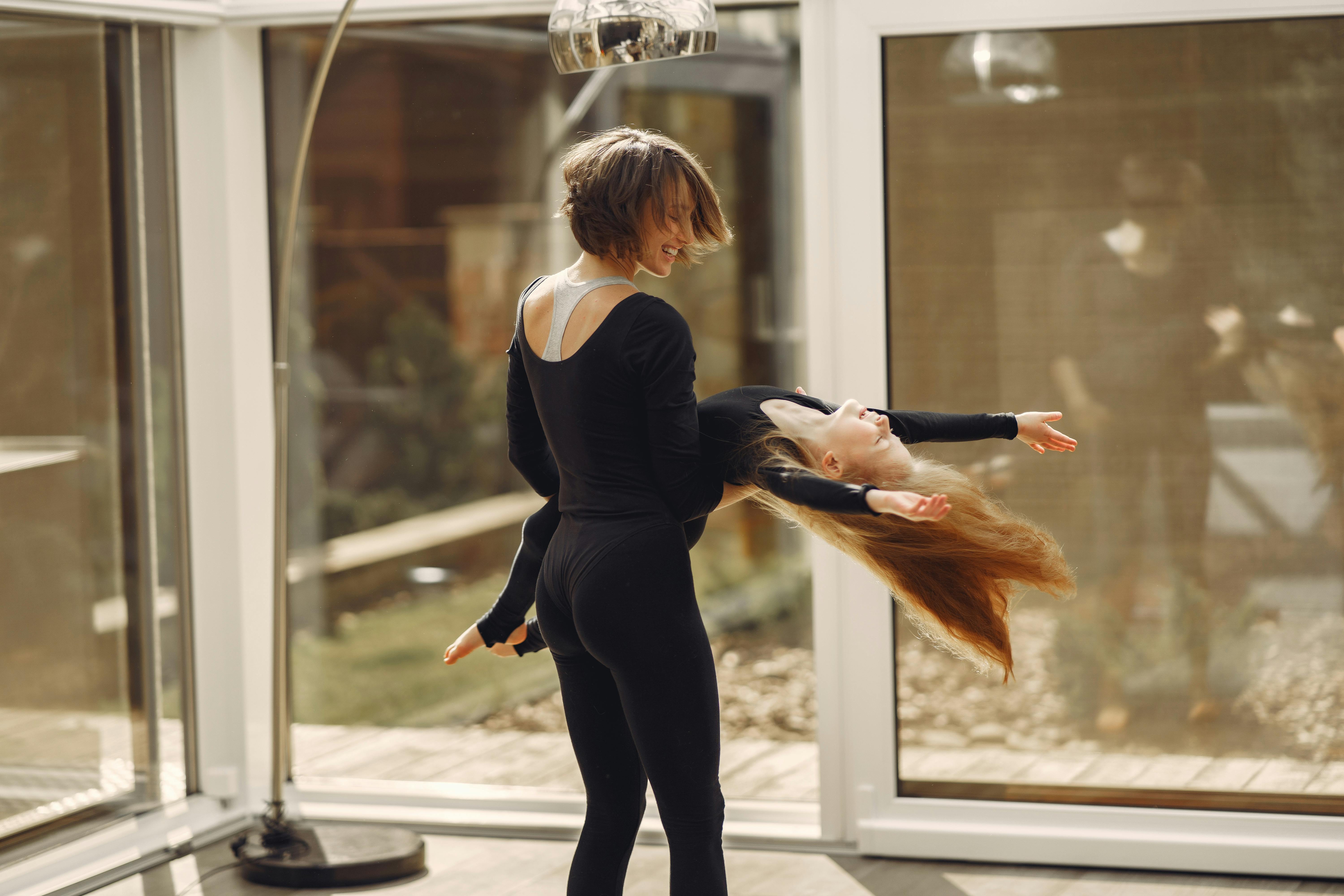 woman in black top and black leggings carrying little girl