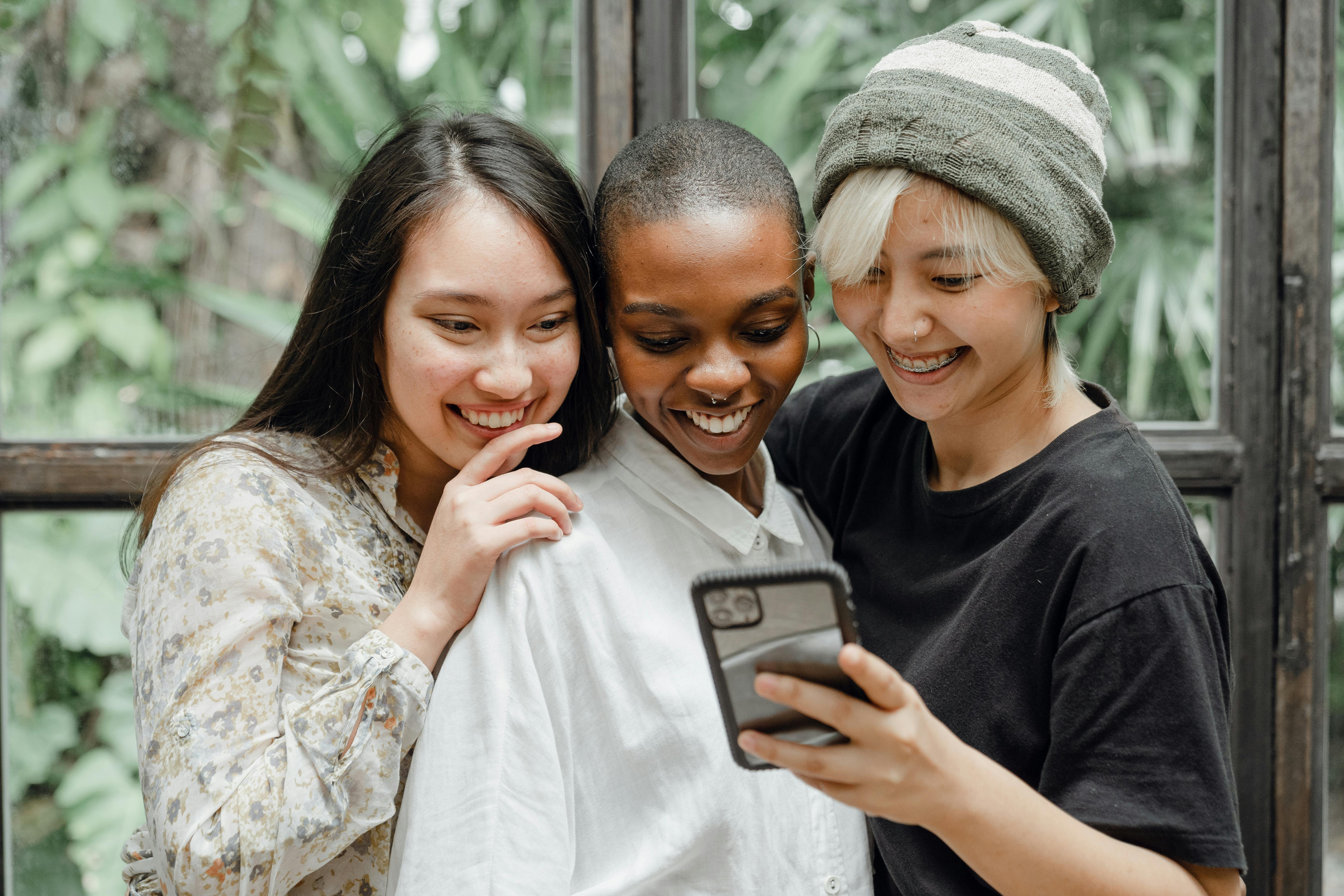 happy young diverse female friends taking selfie on mobile phone