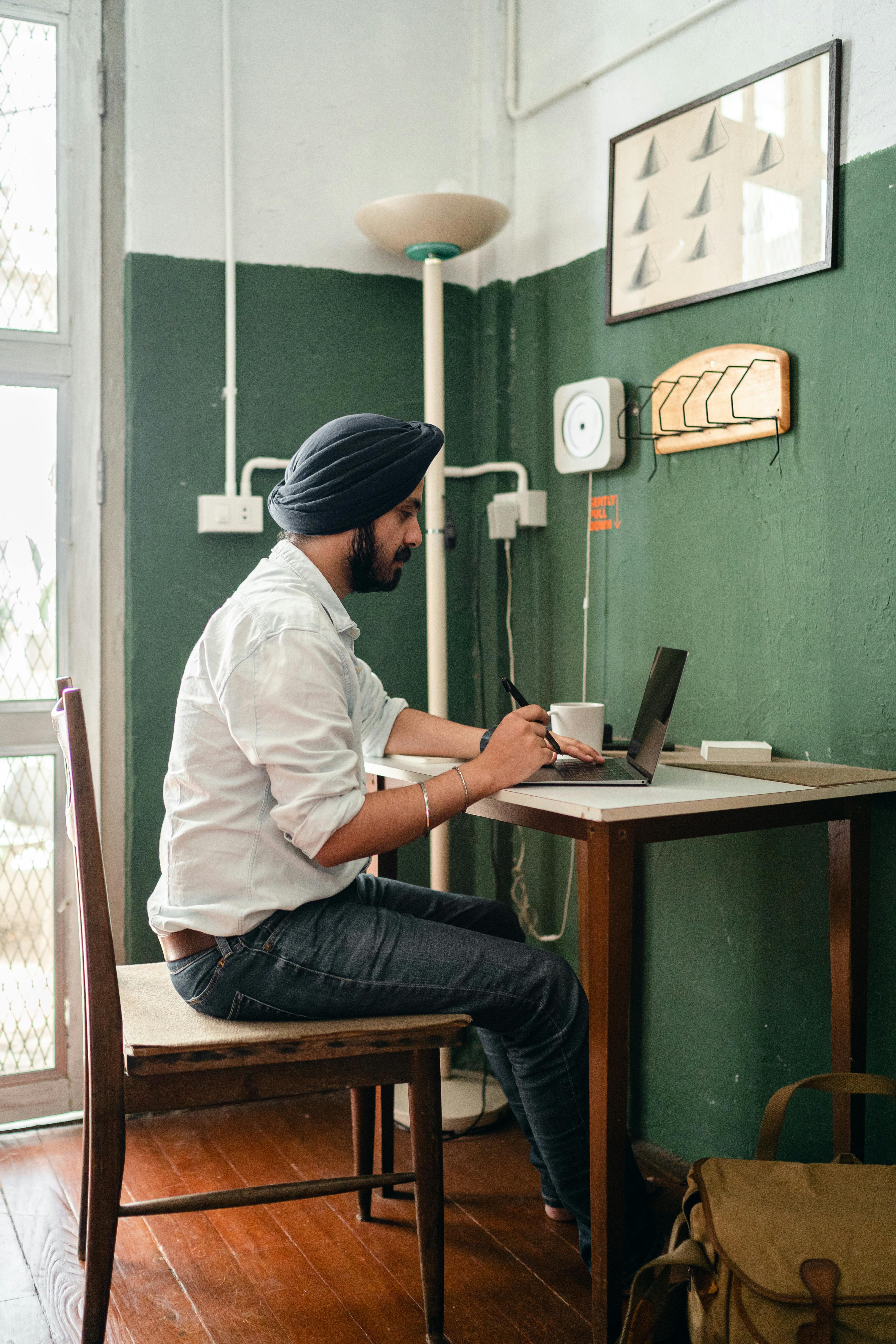 young ethnic man using laptop in modern workplace