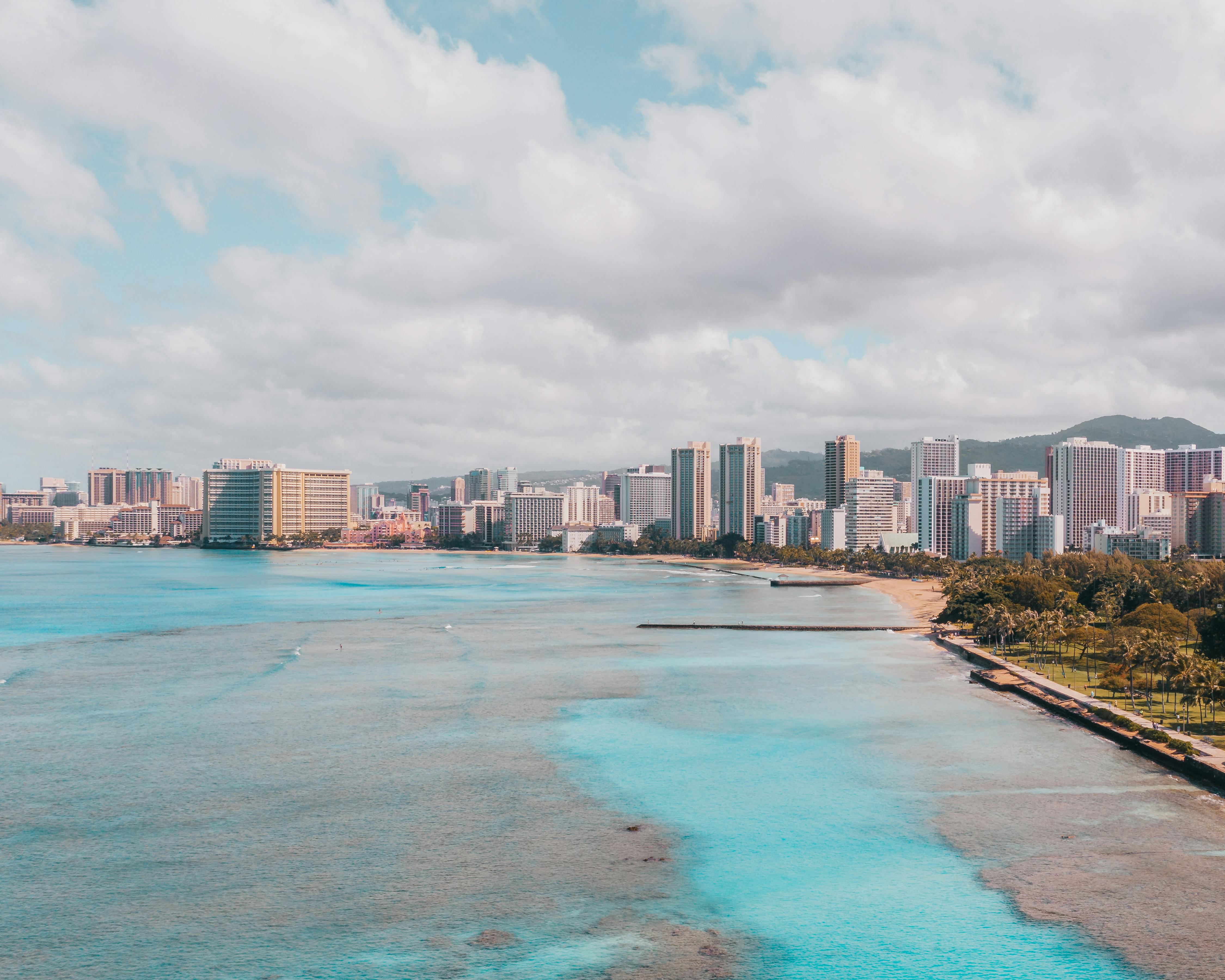 city buildings near body of water under cloudy sky