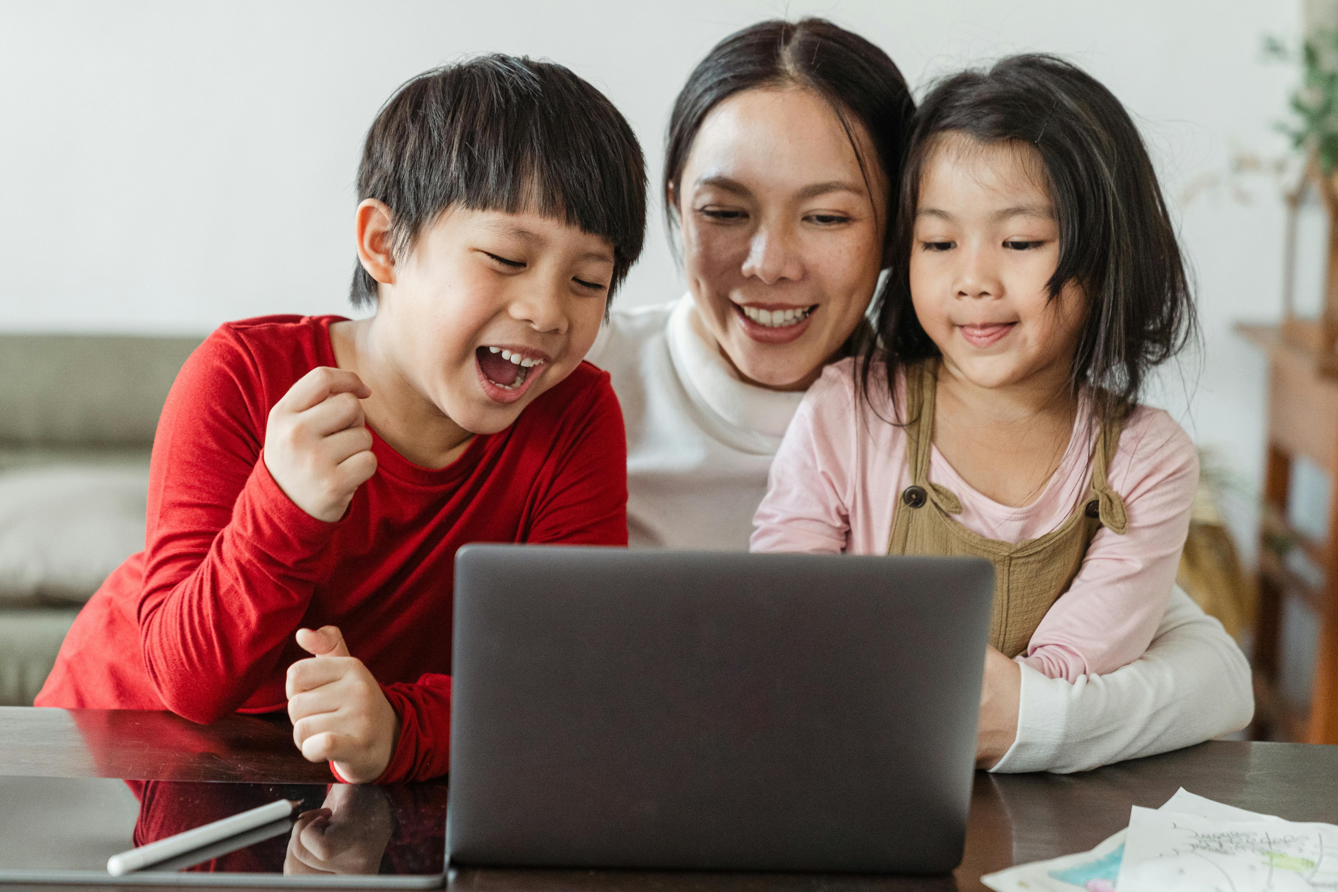 happy ethnic mom and kids watching cartoon on netbook at home