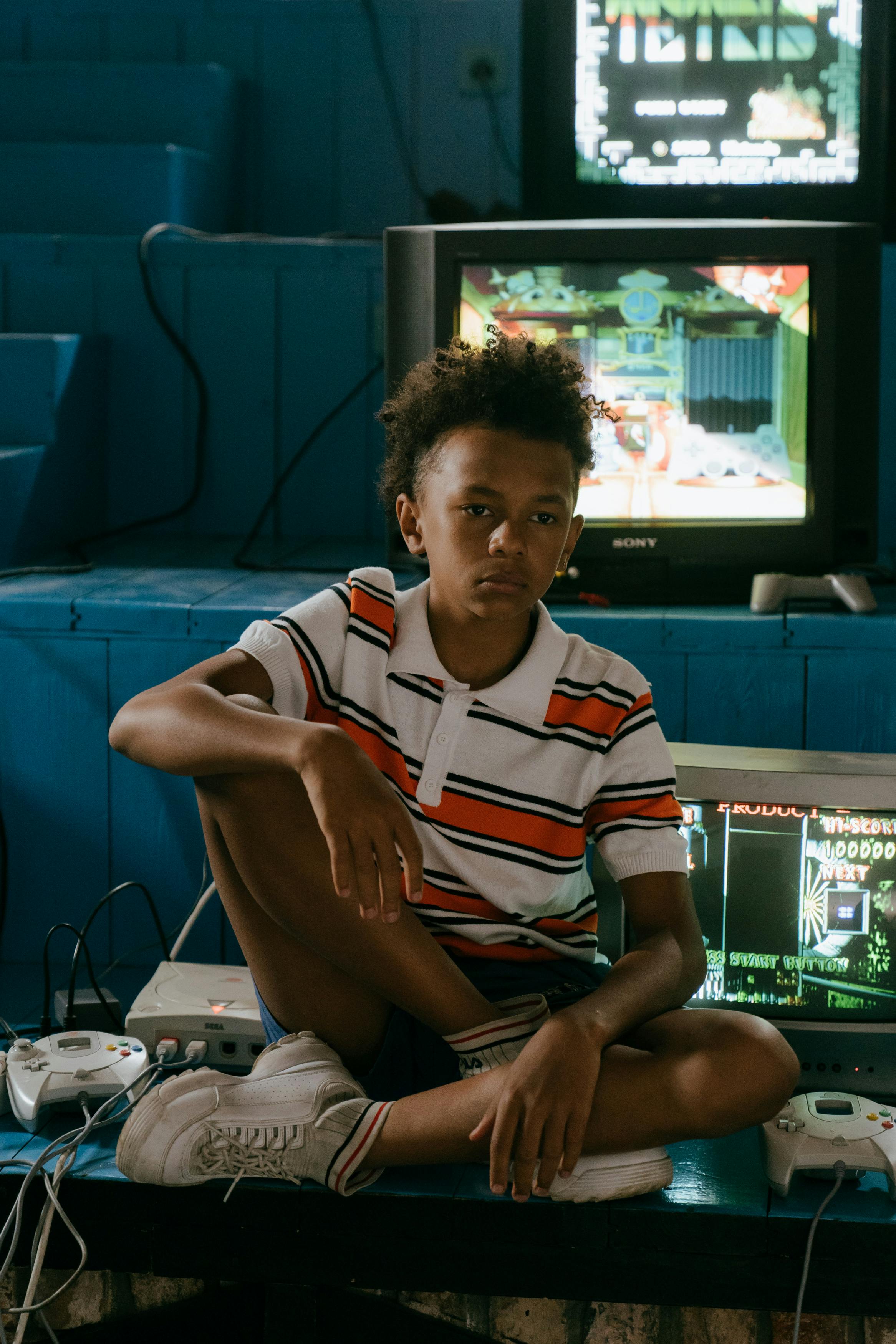 boy in white orange and blue striped polo shirt sitting on chair