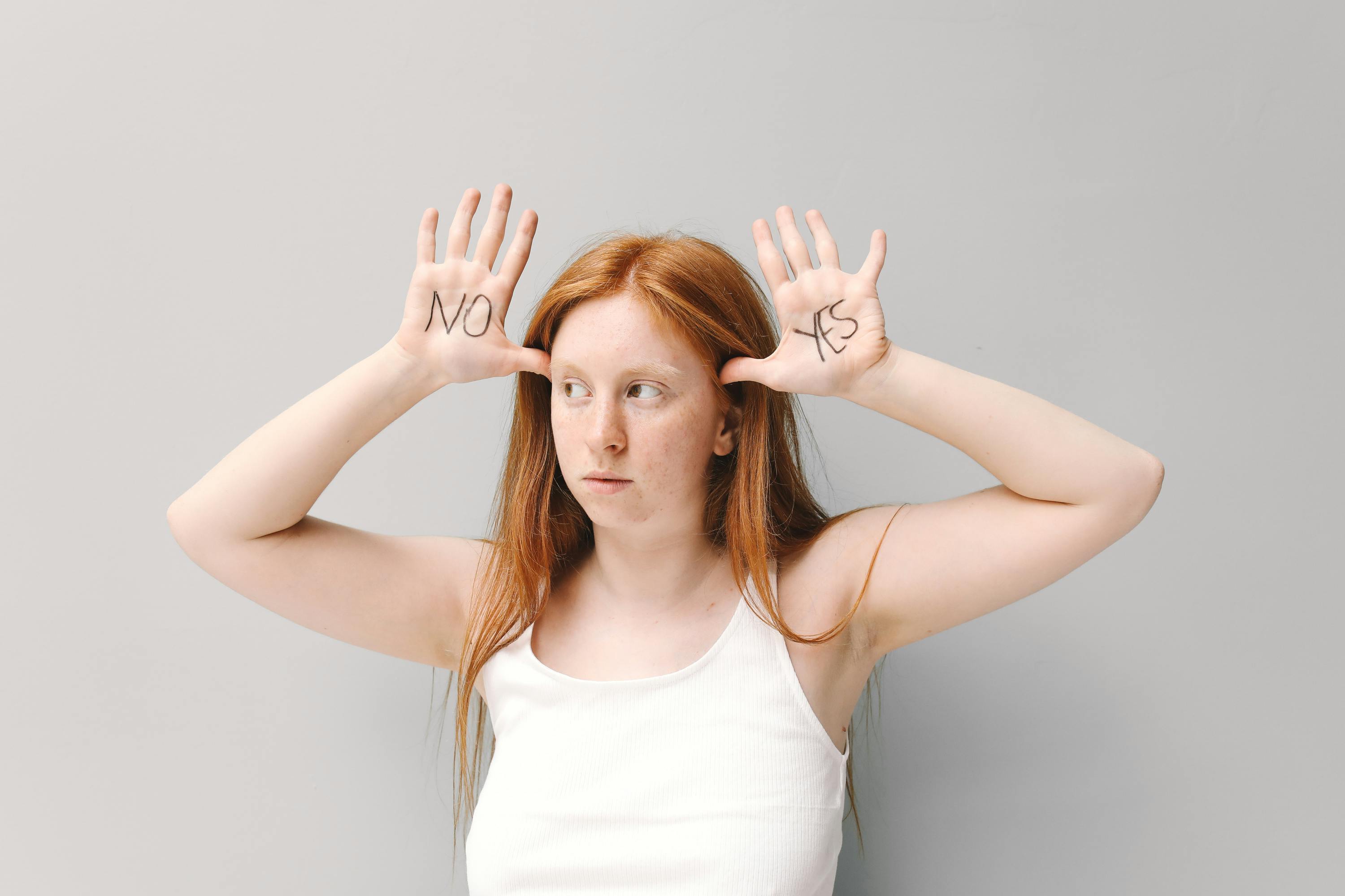 a woman in white tank top with yes and no written on her palms