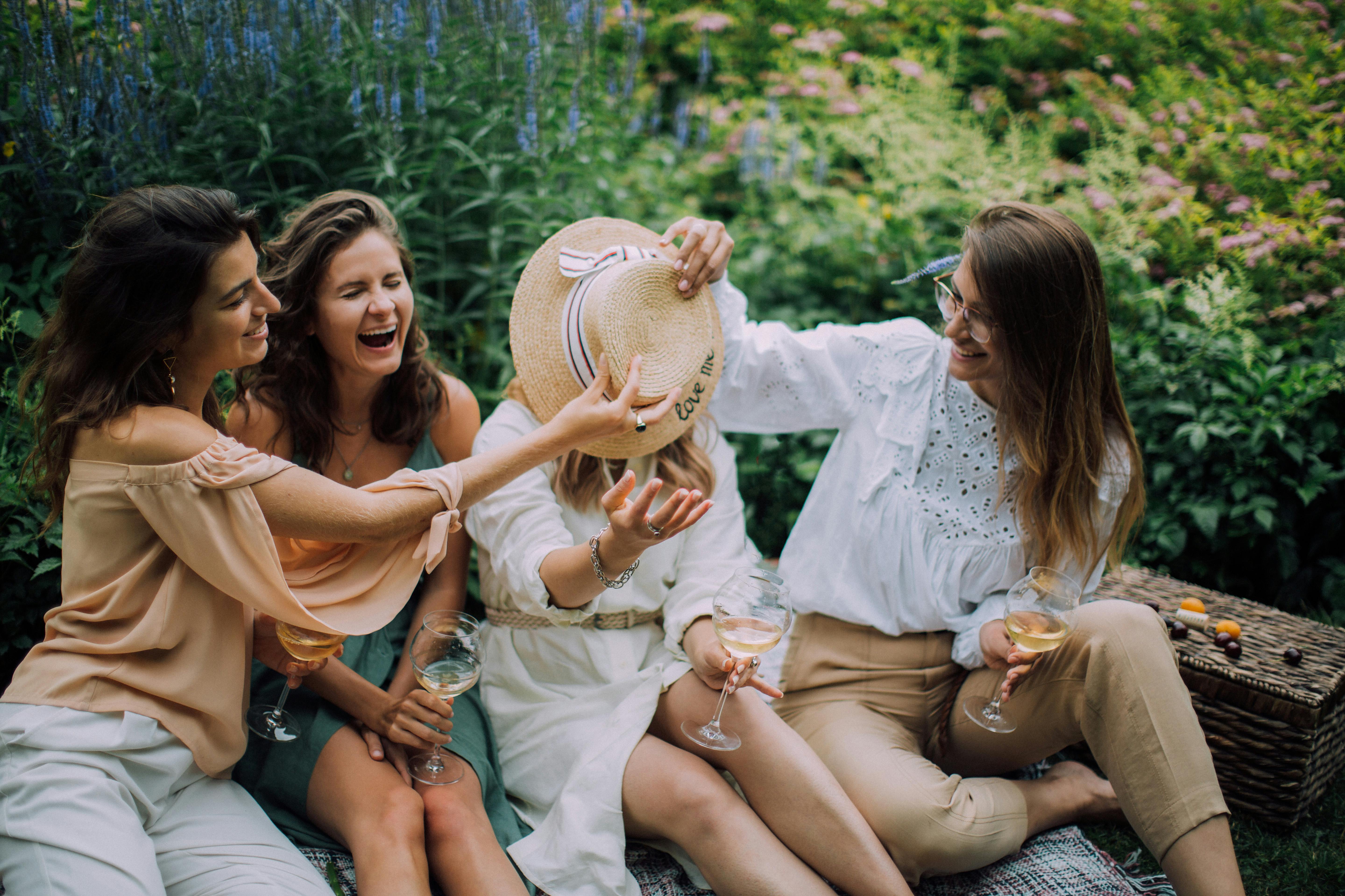 women sitting on a picnic blanket while laughing together