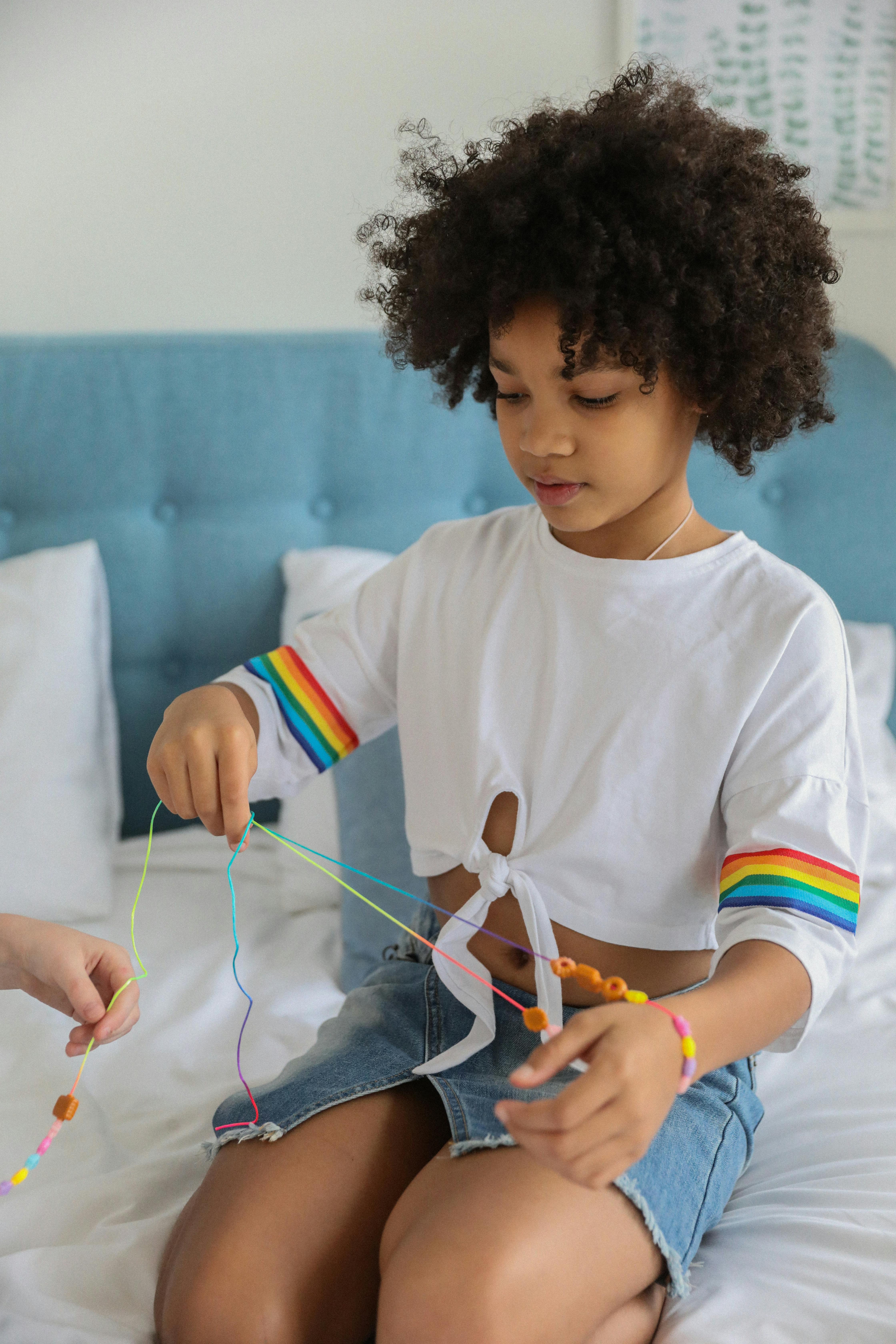 black child with beads near crop friend on bed