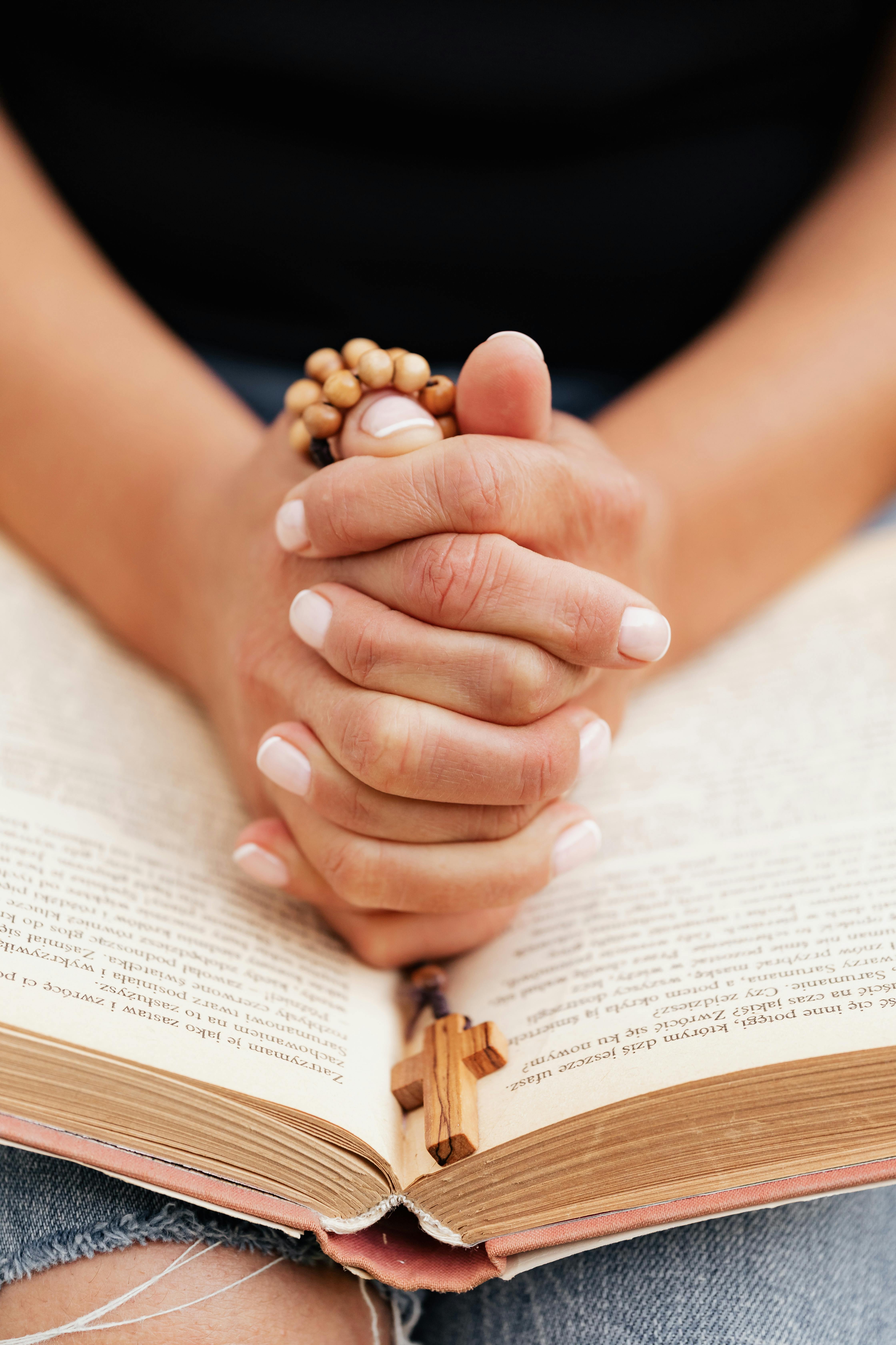 close up shot of a person praying while holding a rosary