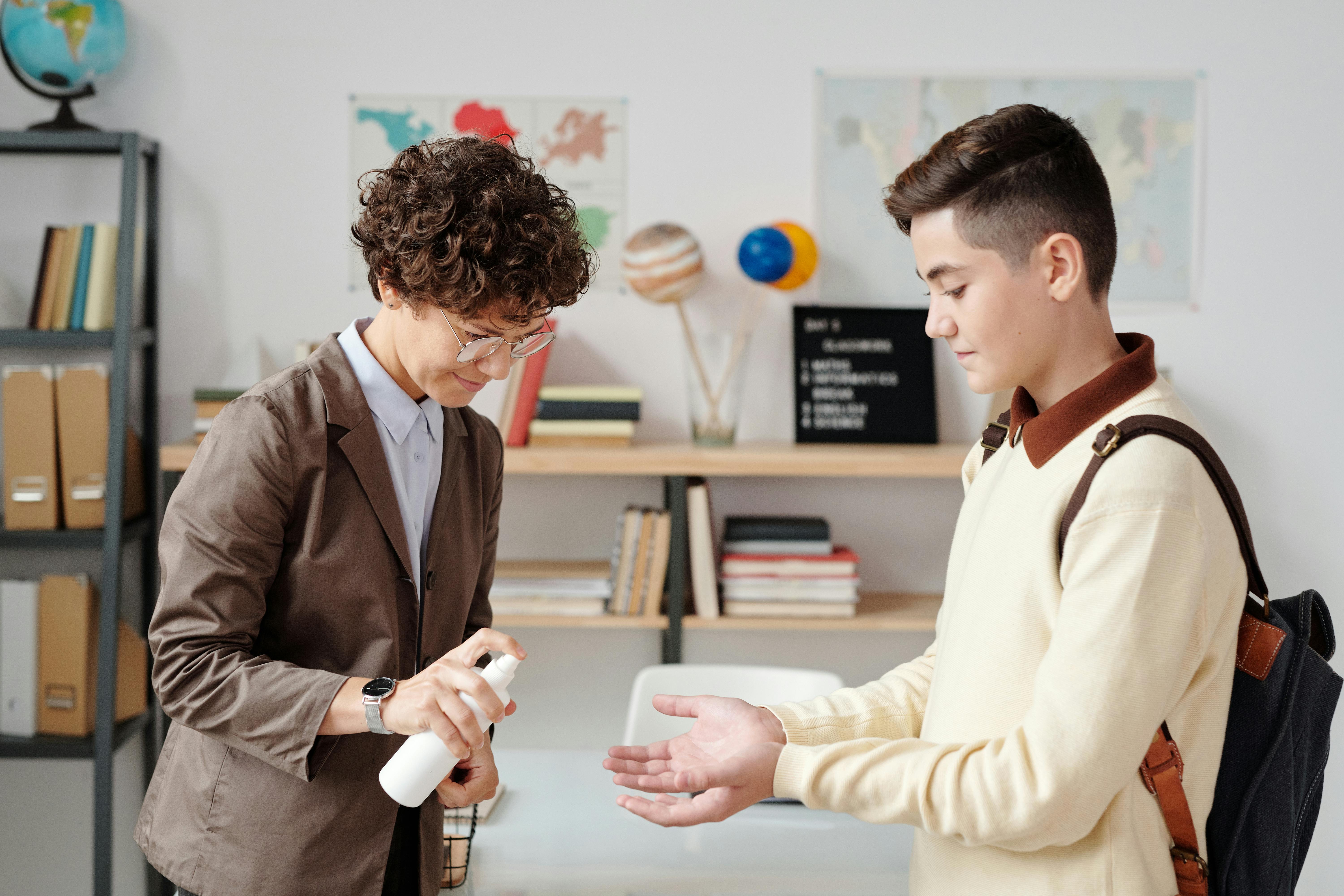 a teacher spraying hand sanitizer