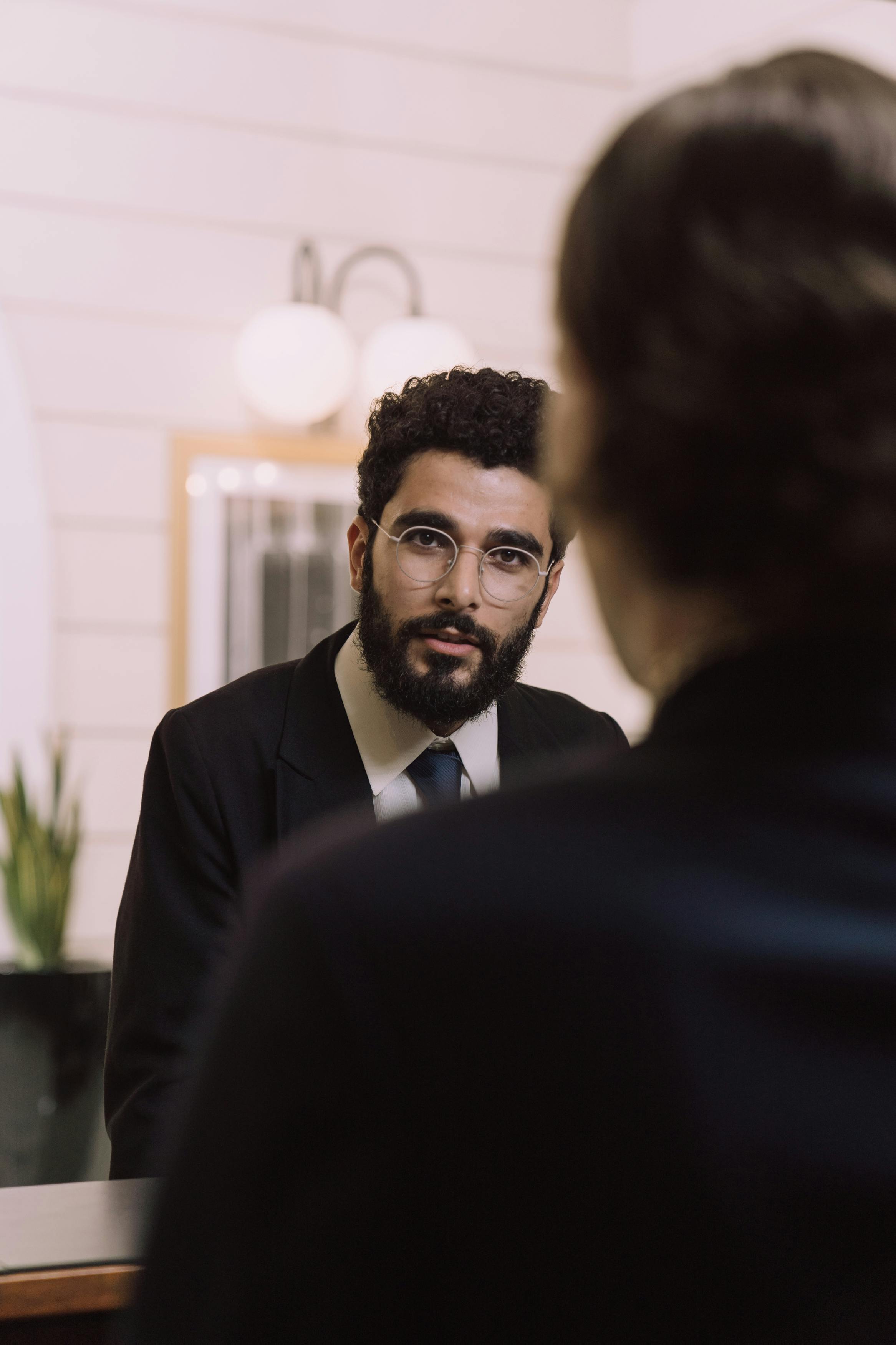 man wearing eyeglasses and black suit jacket standing in front of another person