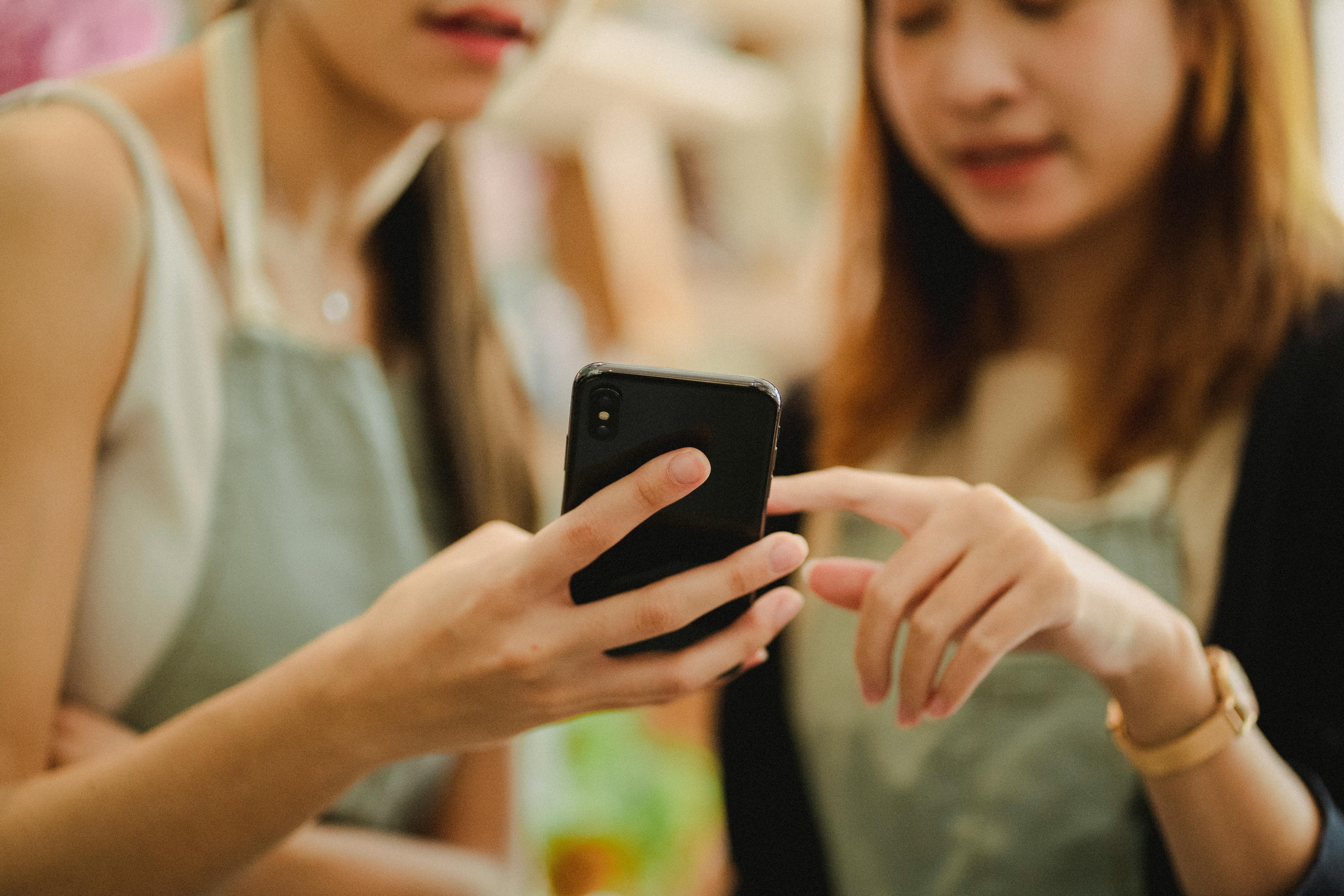 crop women with modern smartphone in shop