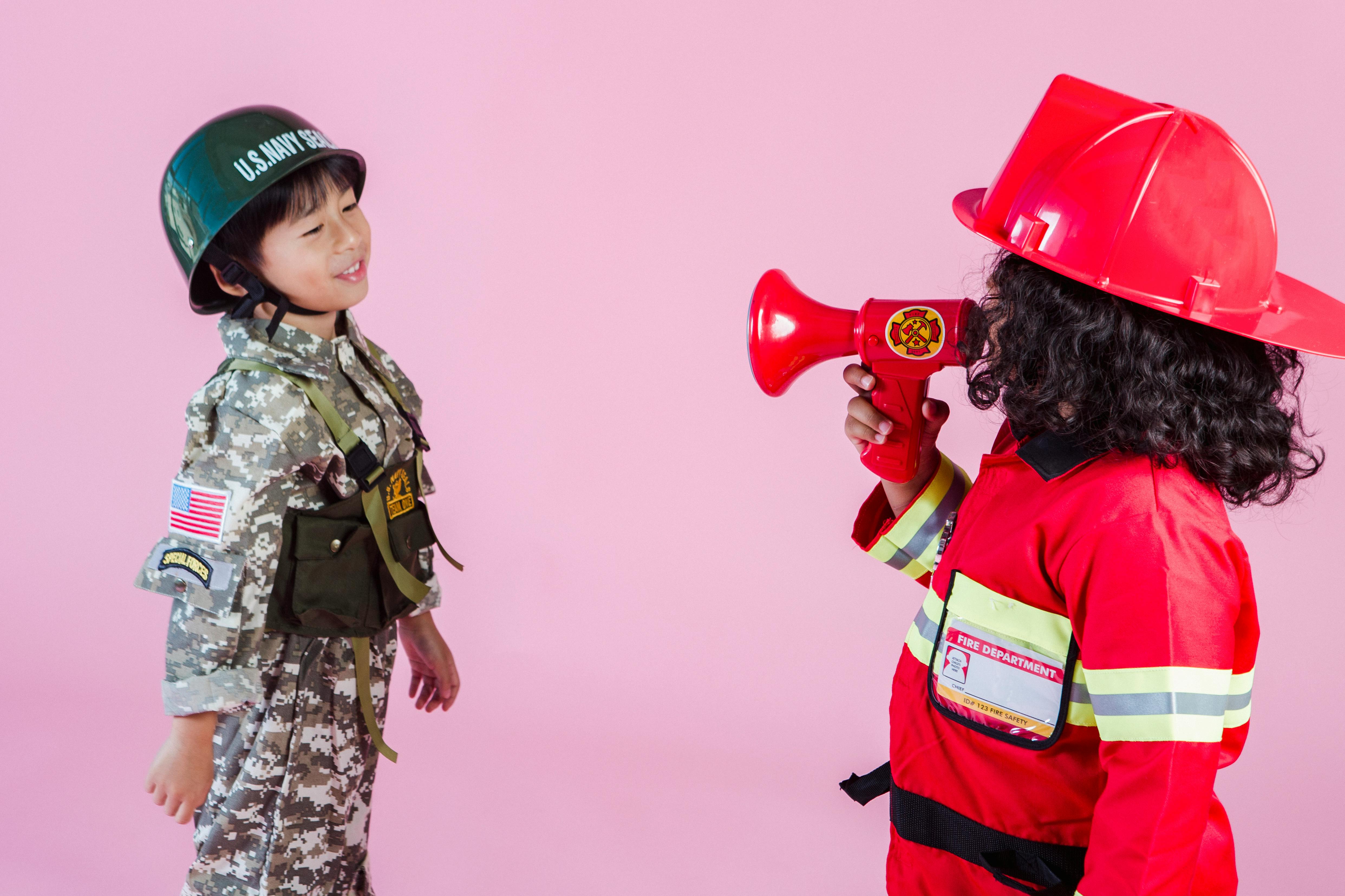 multiracial children in military costume and fireman costume in room