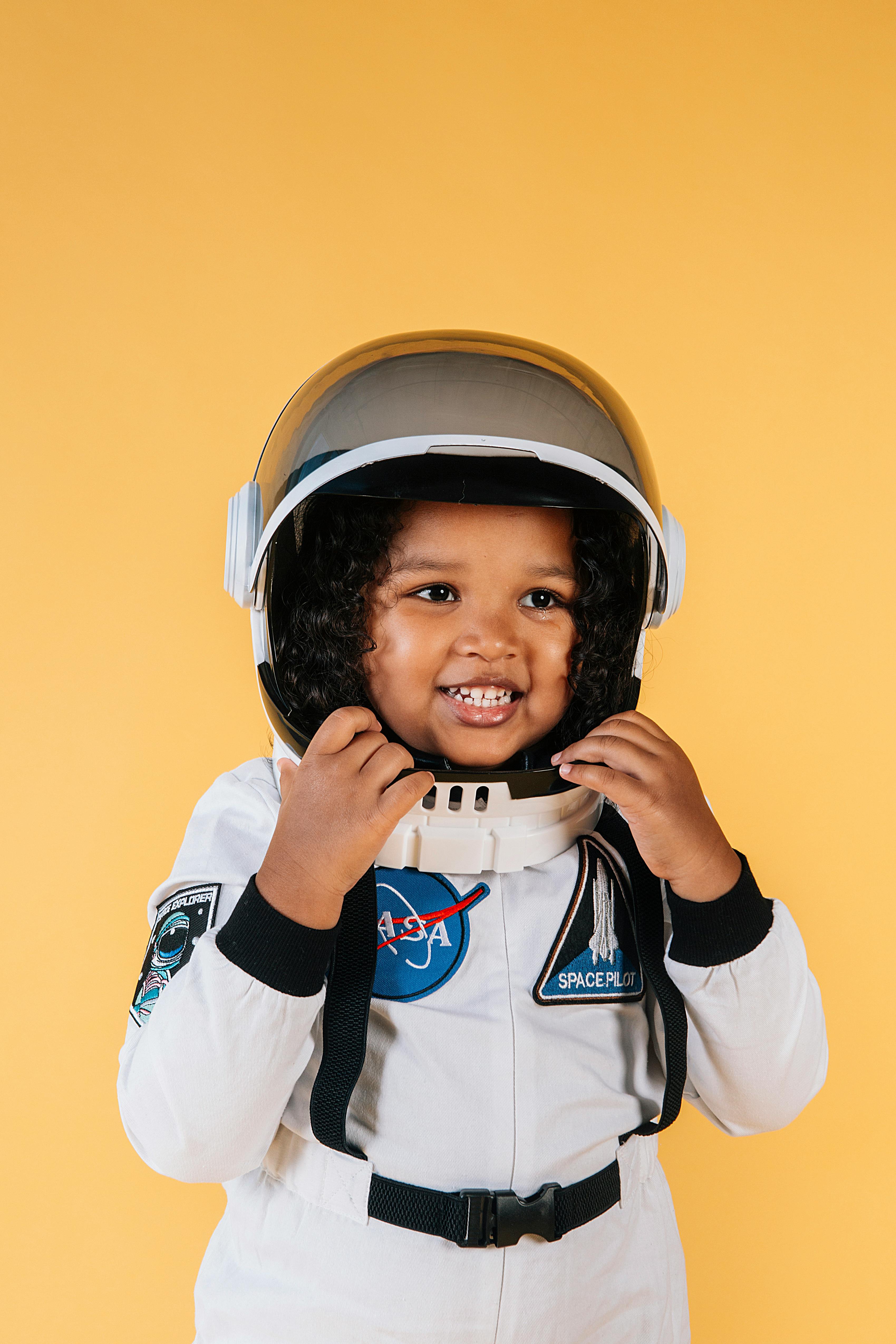 smiling black girl wearing cosmonaut suit and touching helmet