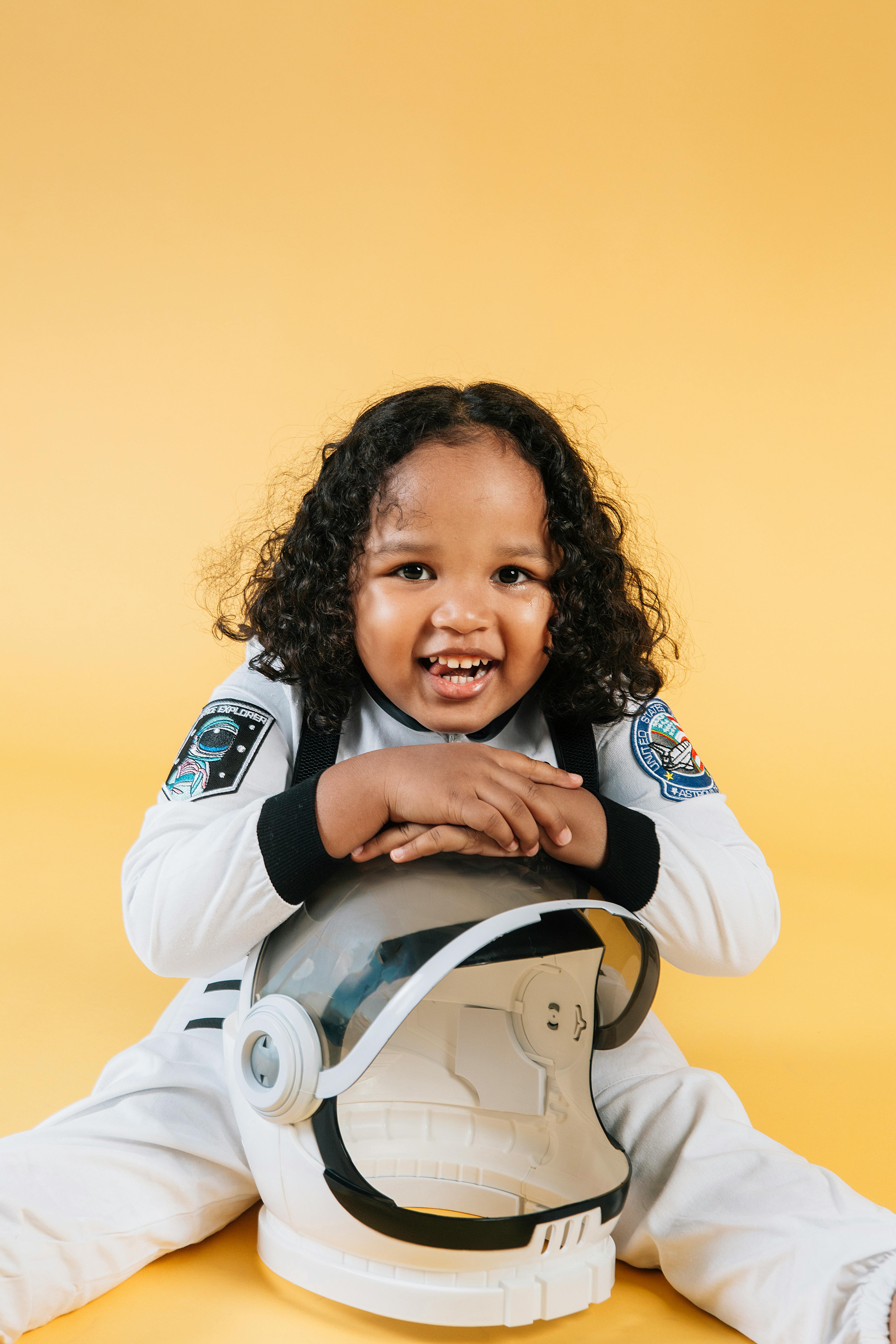 excited black girl in spacesuit sitting on floor