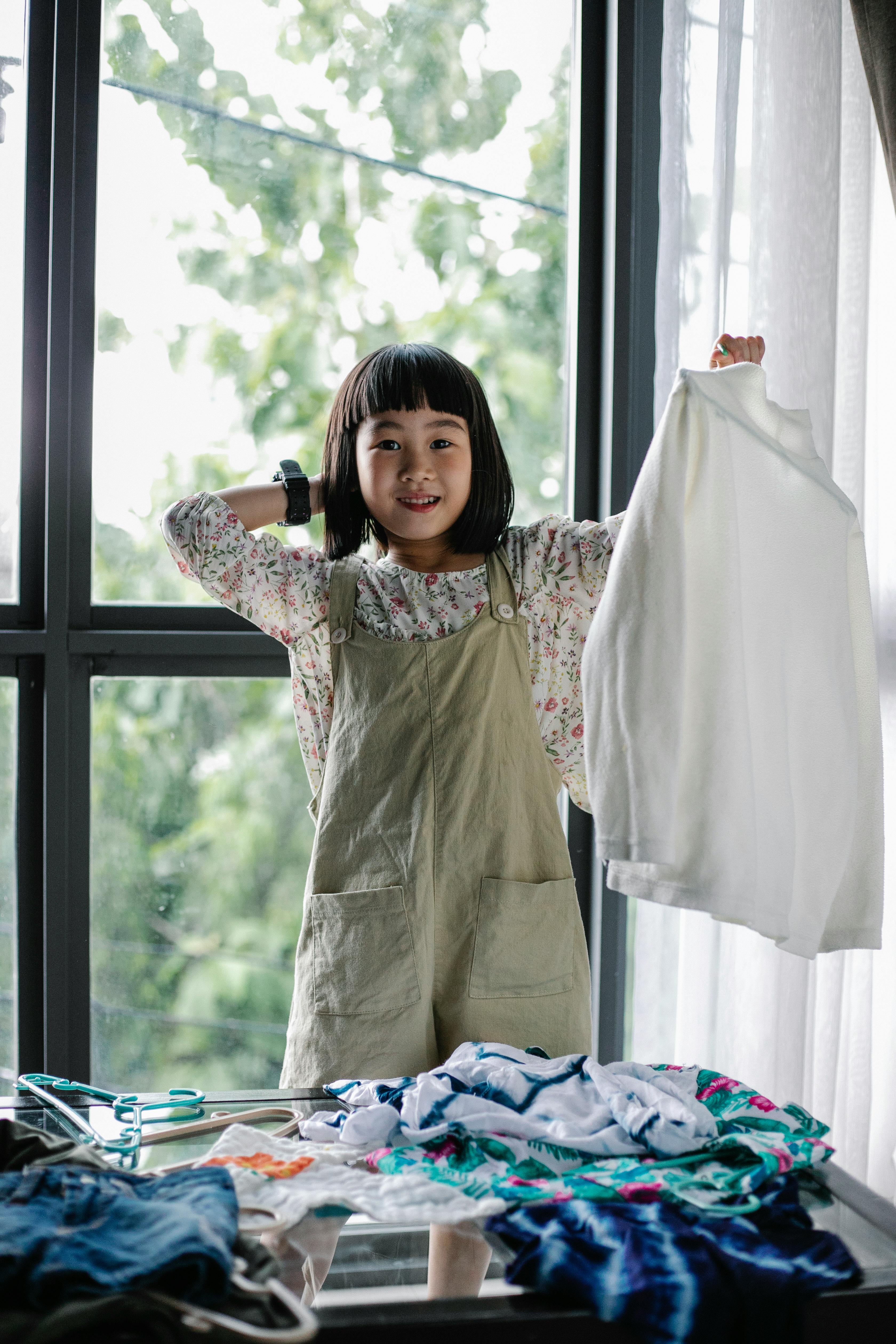 cheerful asian girl sorting clothes heaped on table