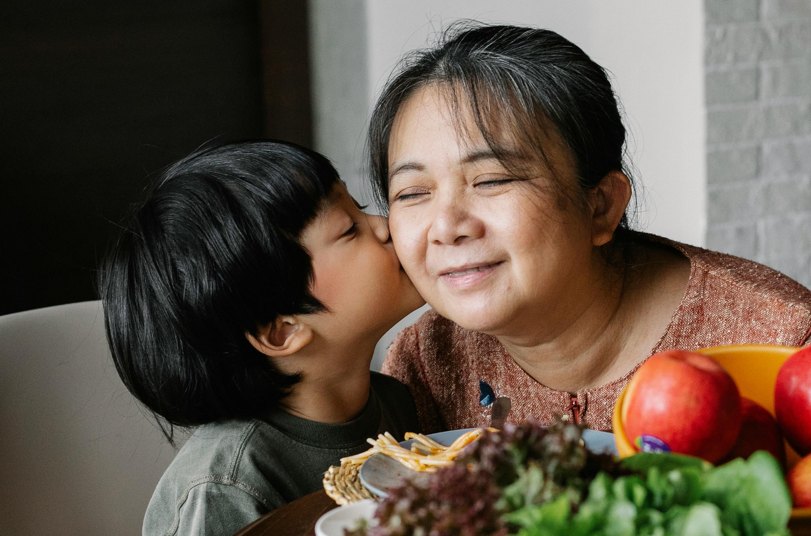 asian little boy kissing grandmother in cheek