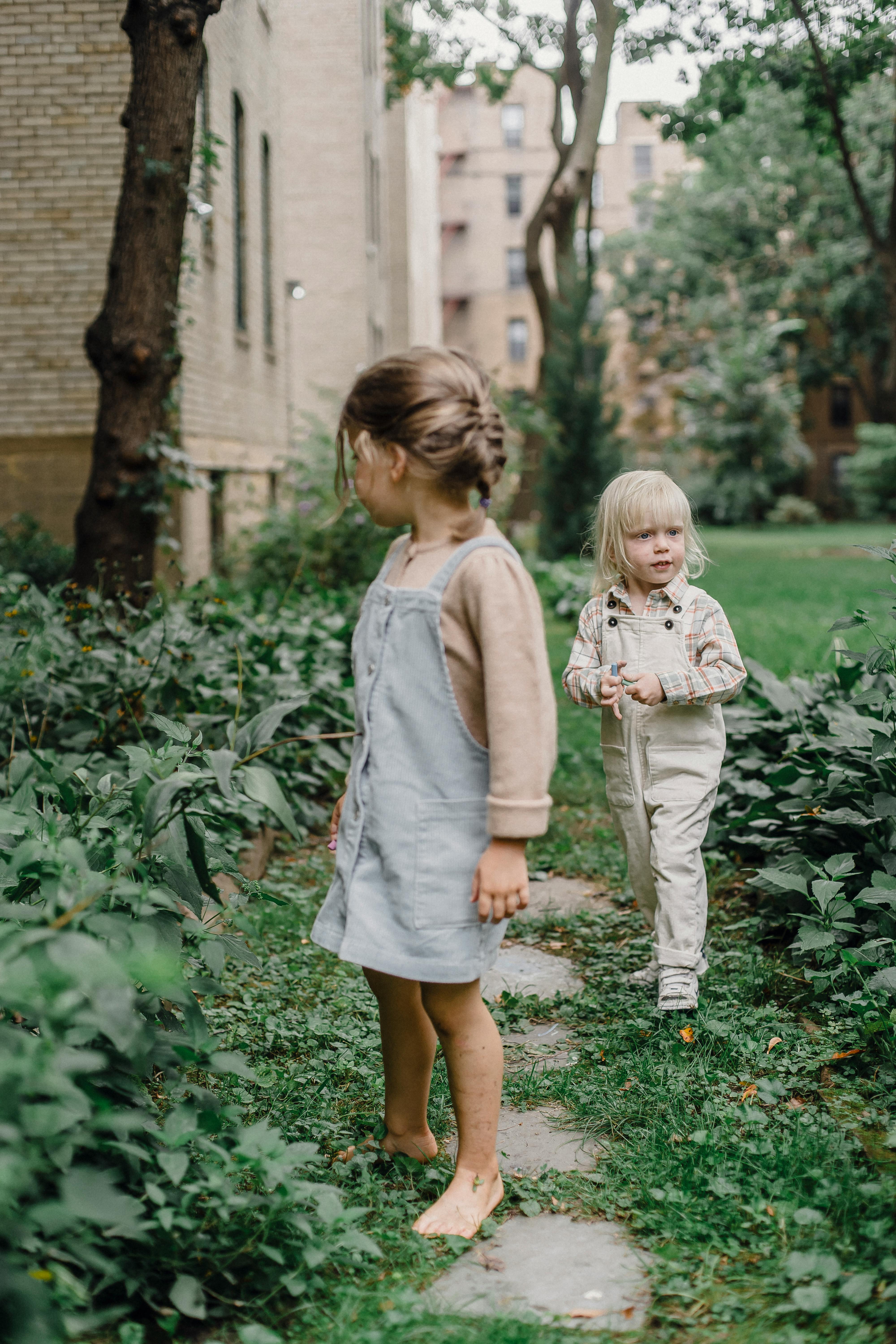 cute siblings walking on pathway in garden