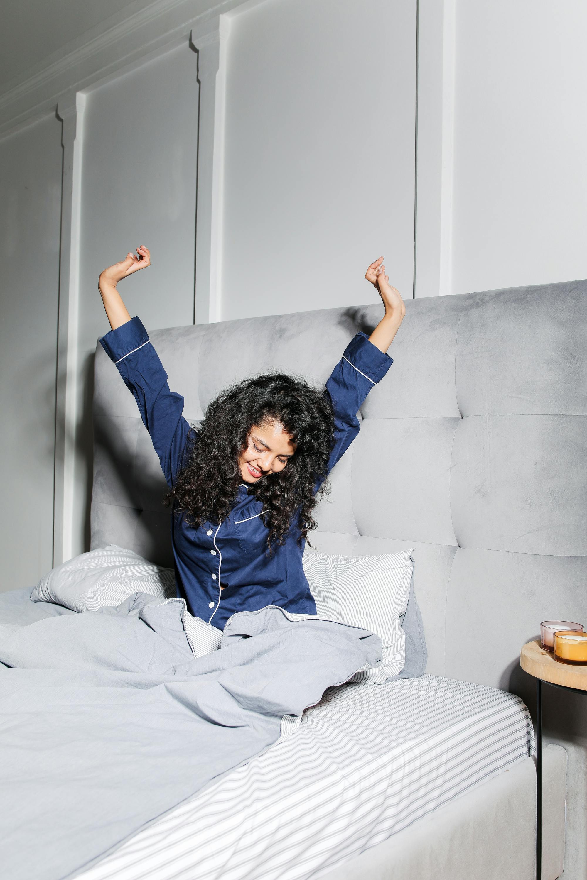 woman with curly hair sitting on bed