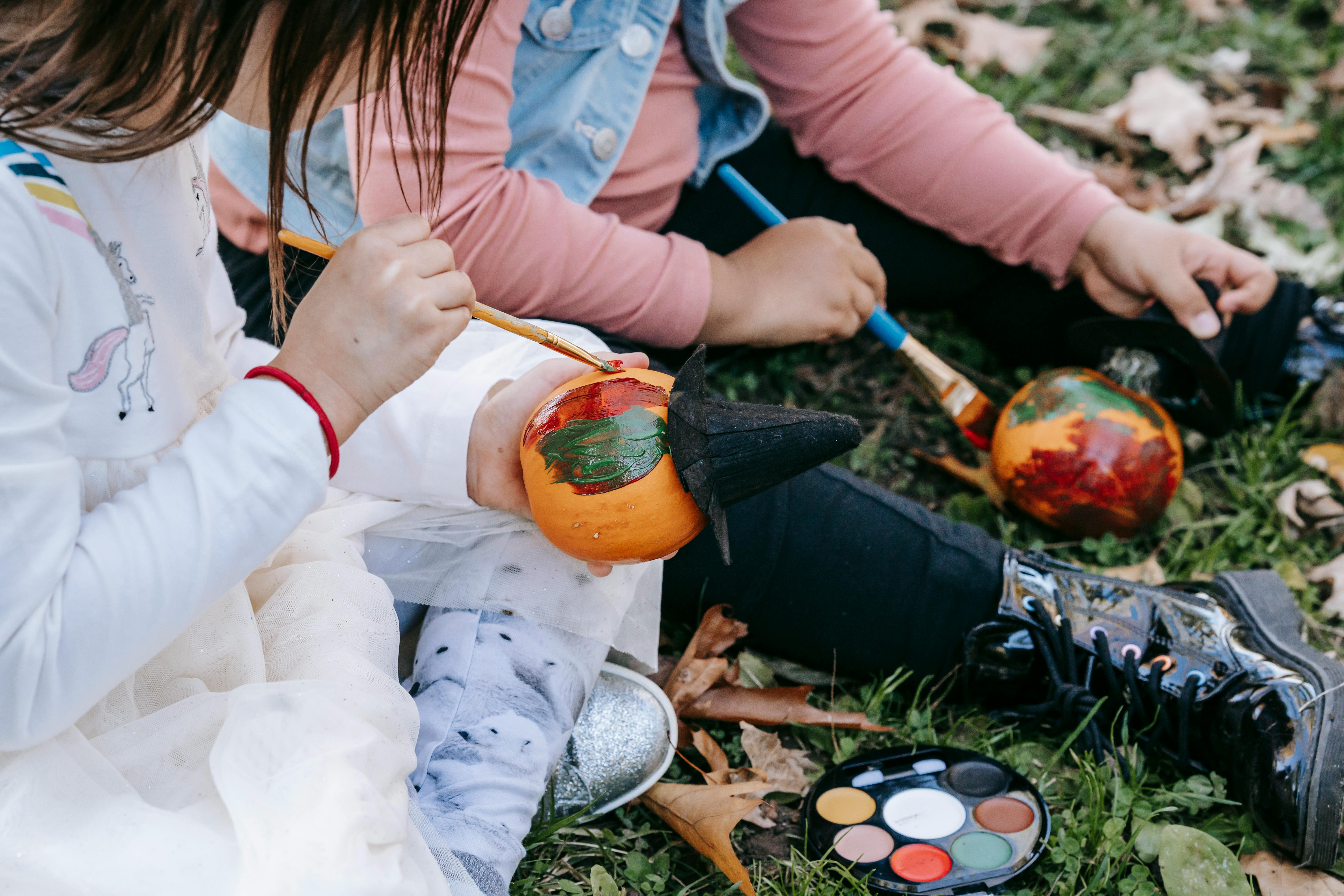 little diverse girls decorating pumpkin with paint