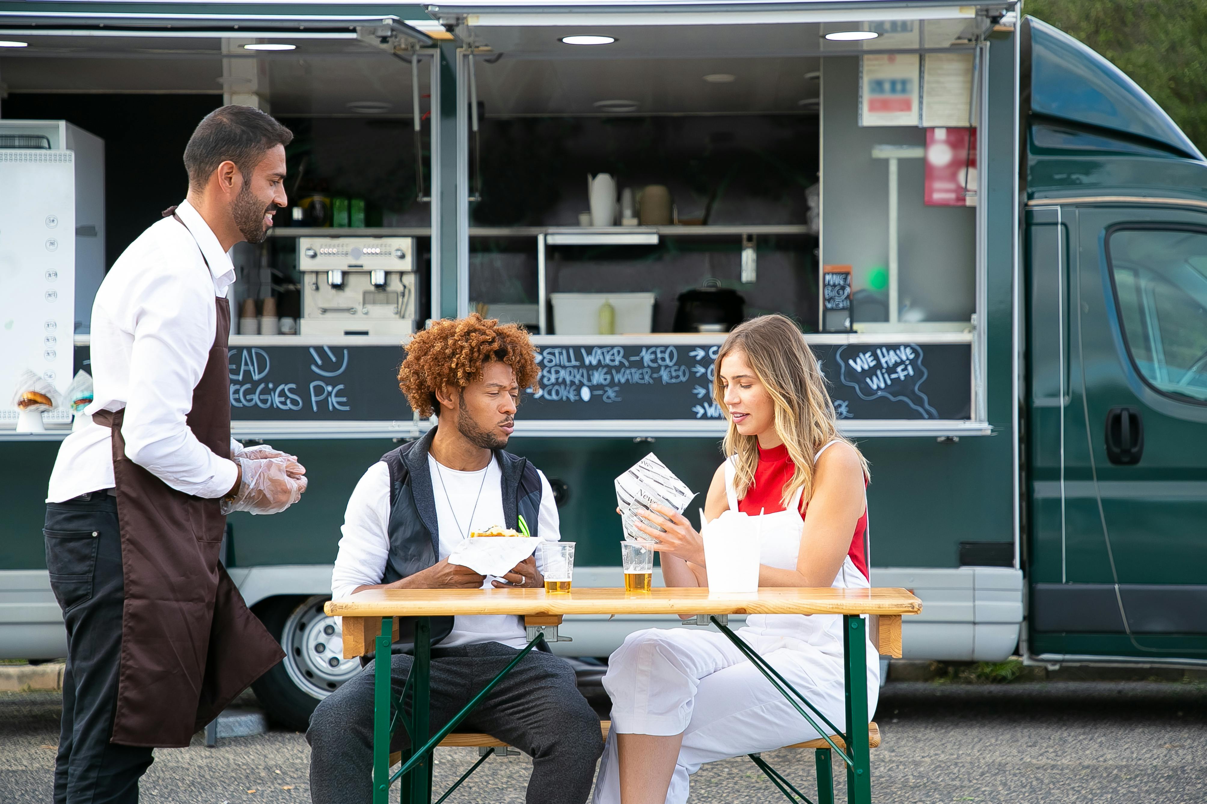 friends eating burgers in street from food truck