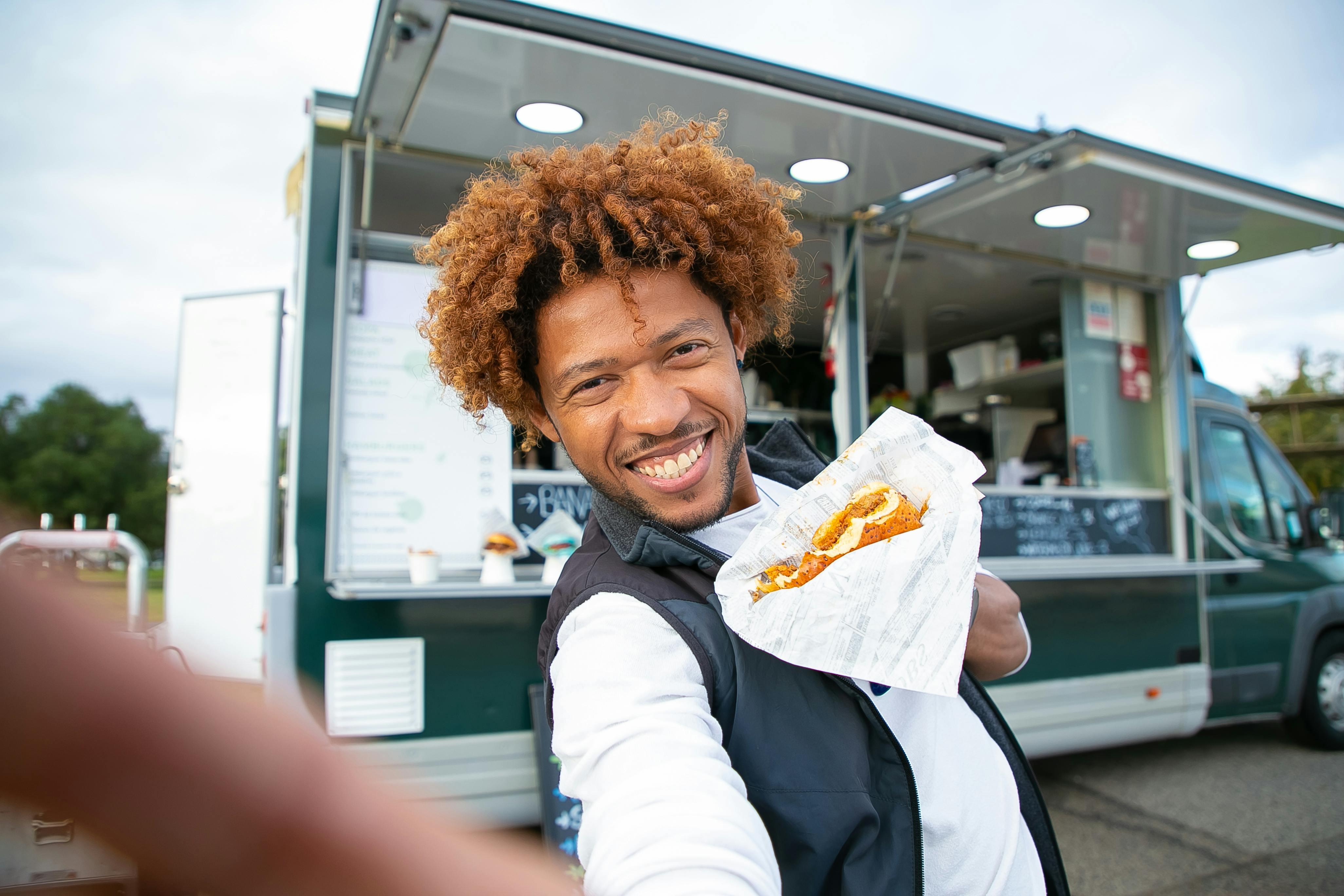 smiling black man eating burger and taking selfie