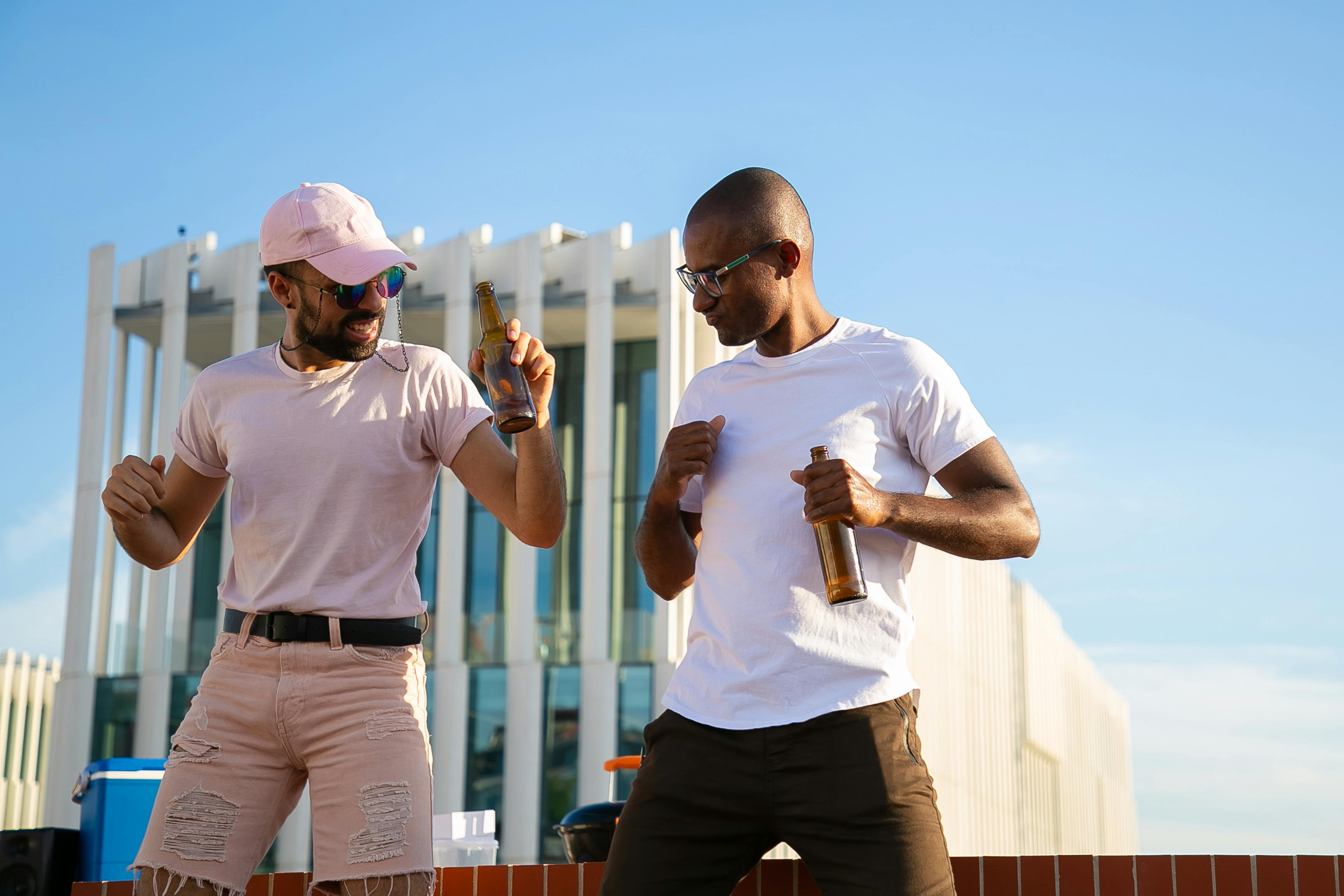 cheerful diverse men having drinks and chatting on rooftop