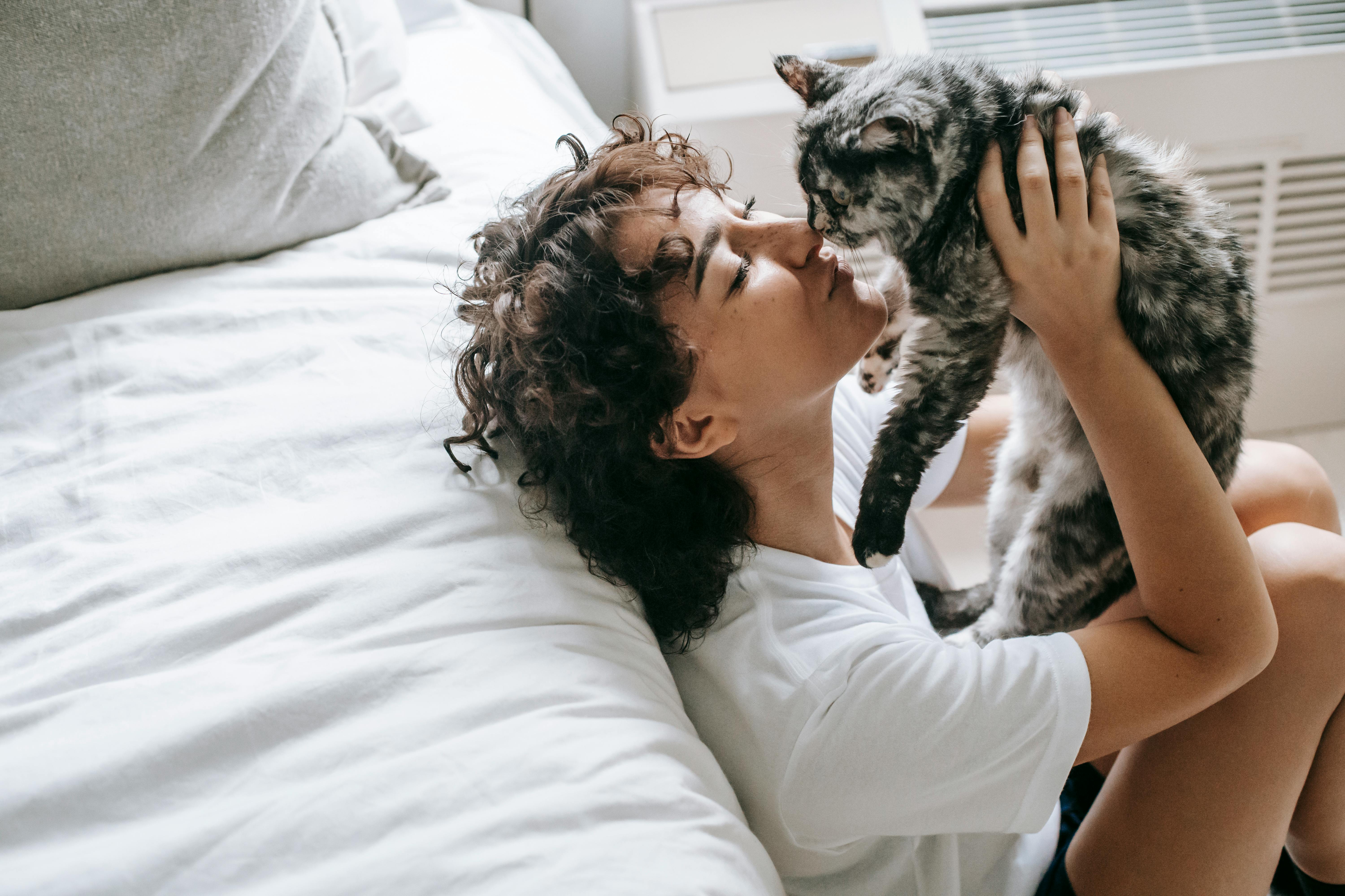 content woman caressing cat in hands chilling in bedroom