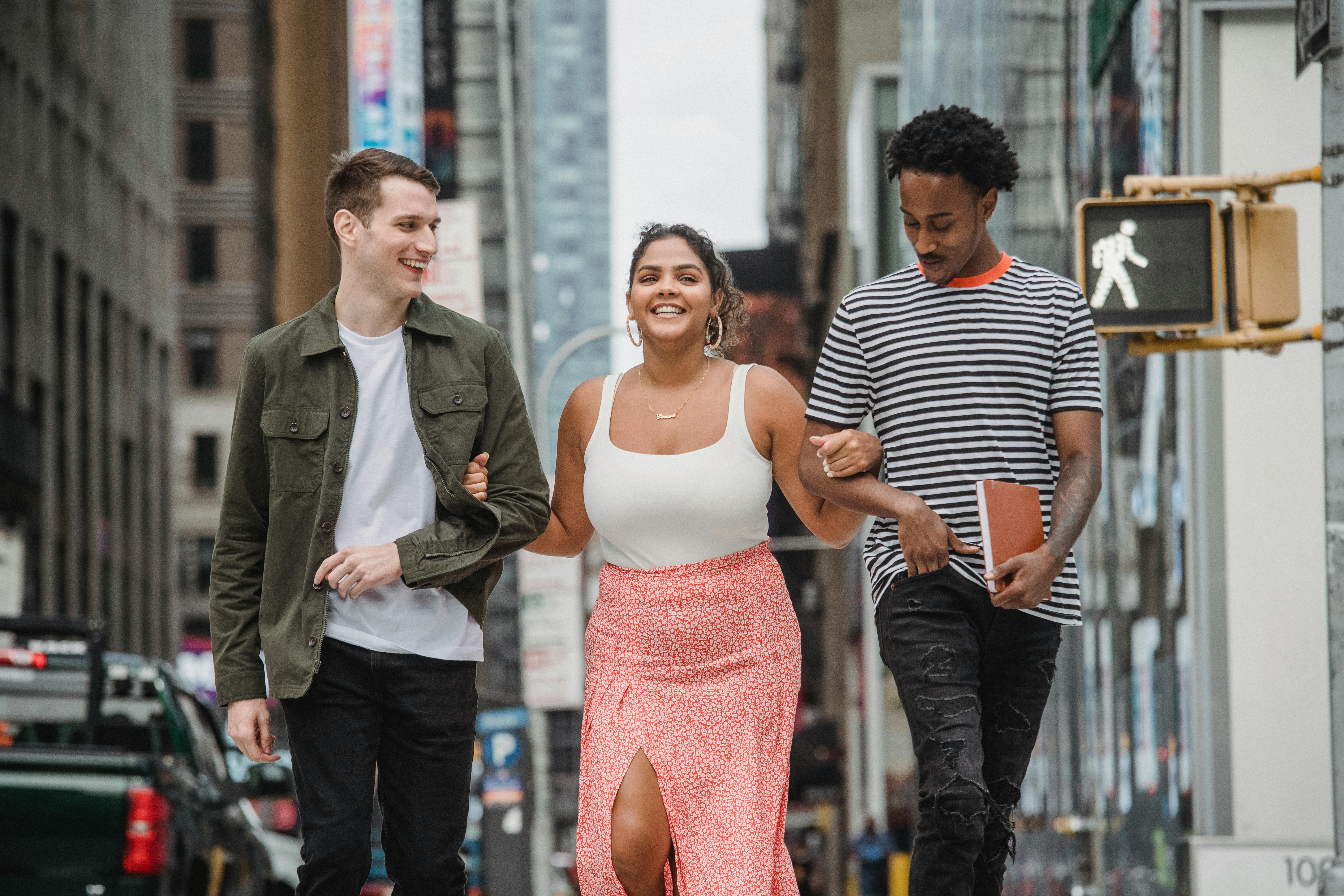 cheerful diverse students smiling and crossing road in city district