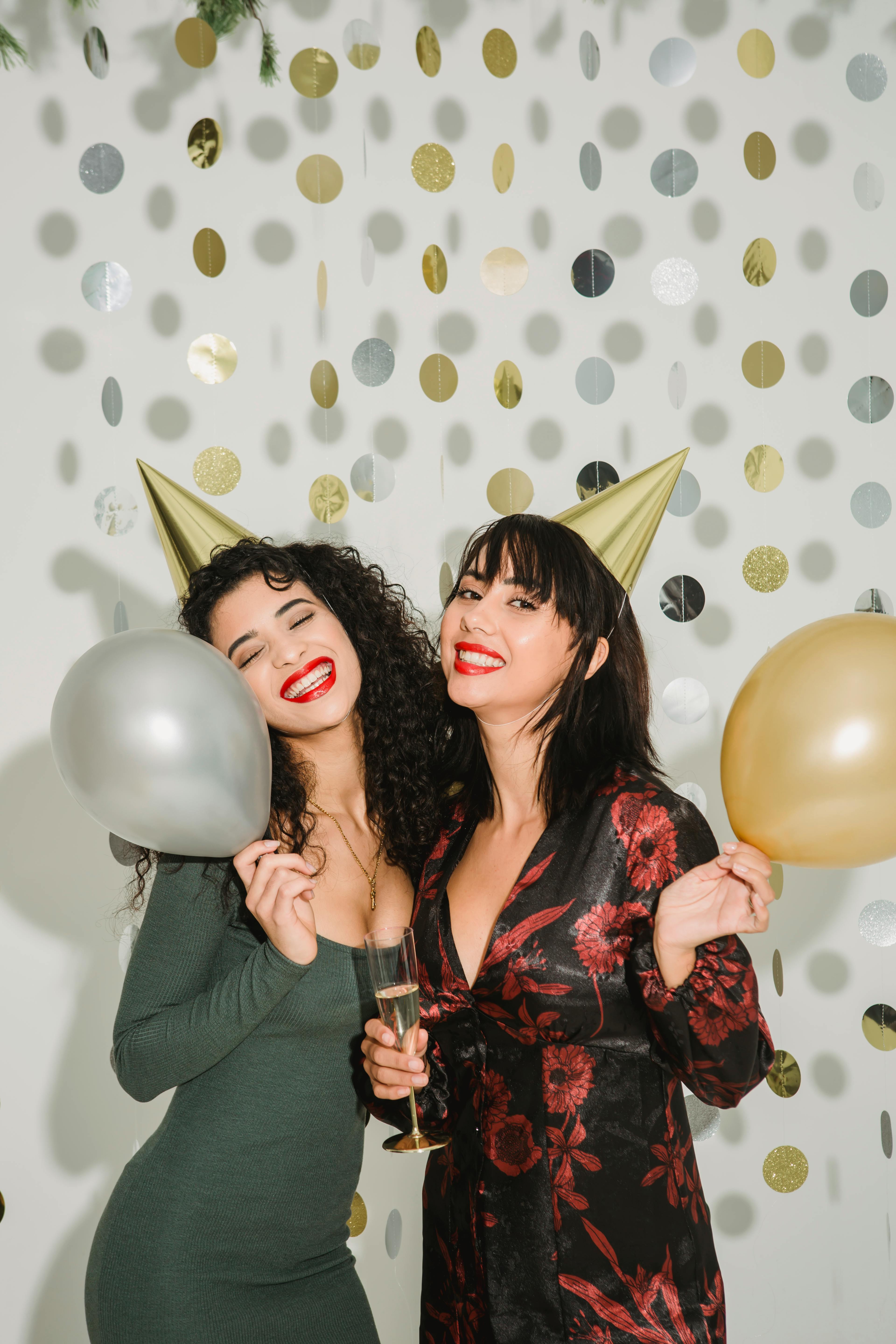 excited women with balloons near paper garland